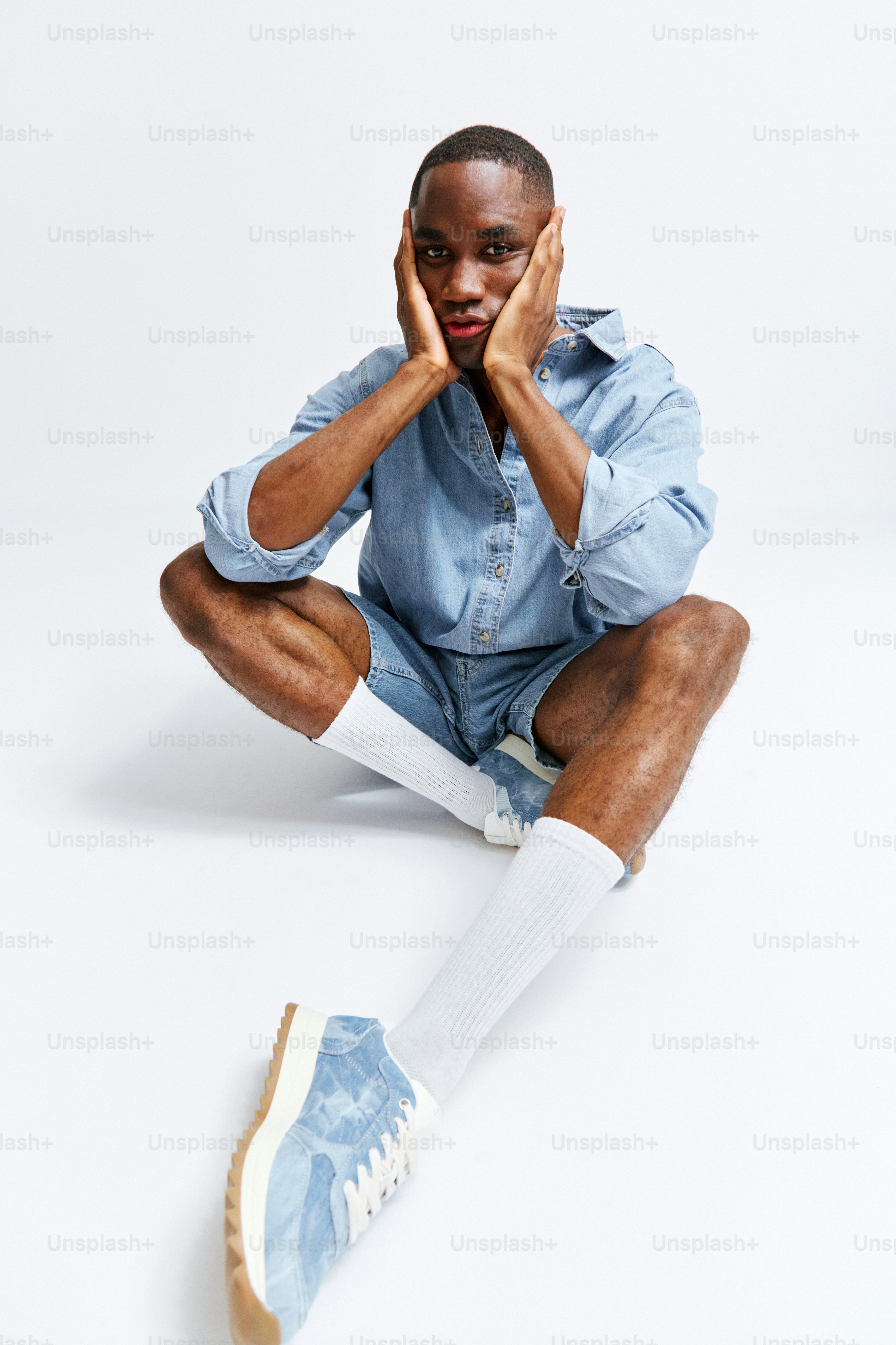 Un hombre sentado en el suelo con las manos en la cara