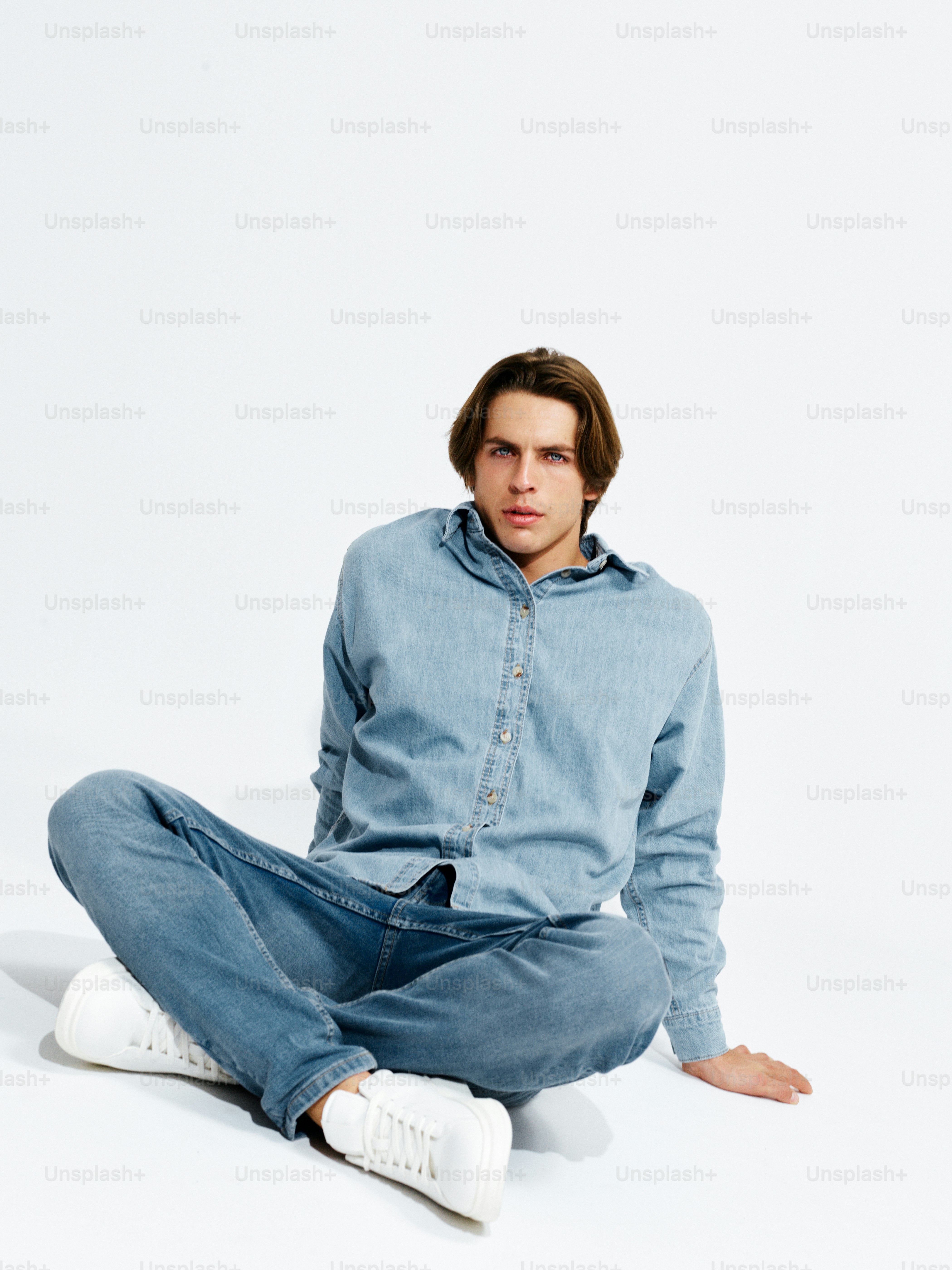 A man sitting on the ground with his hands in his pockets photo ...