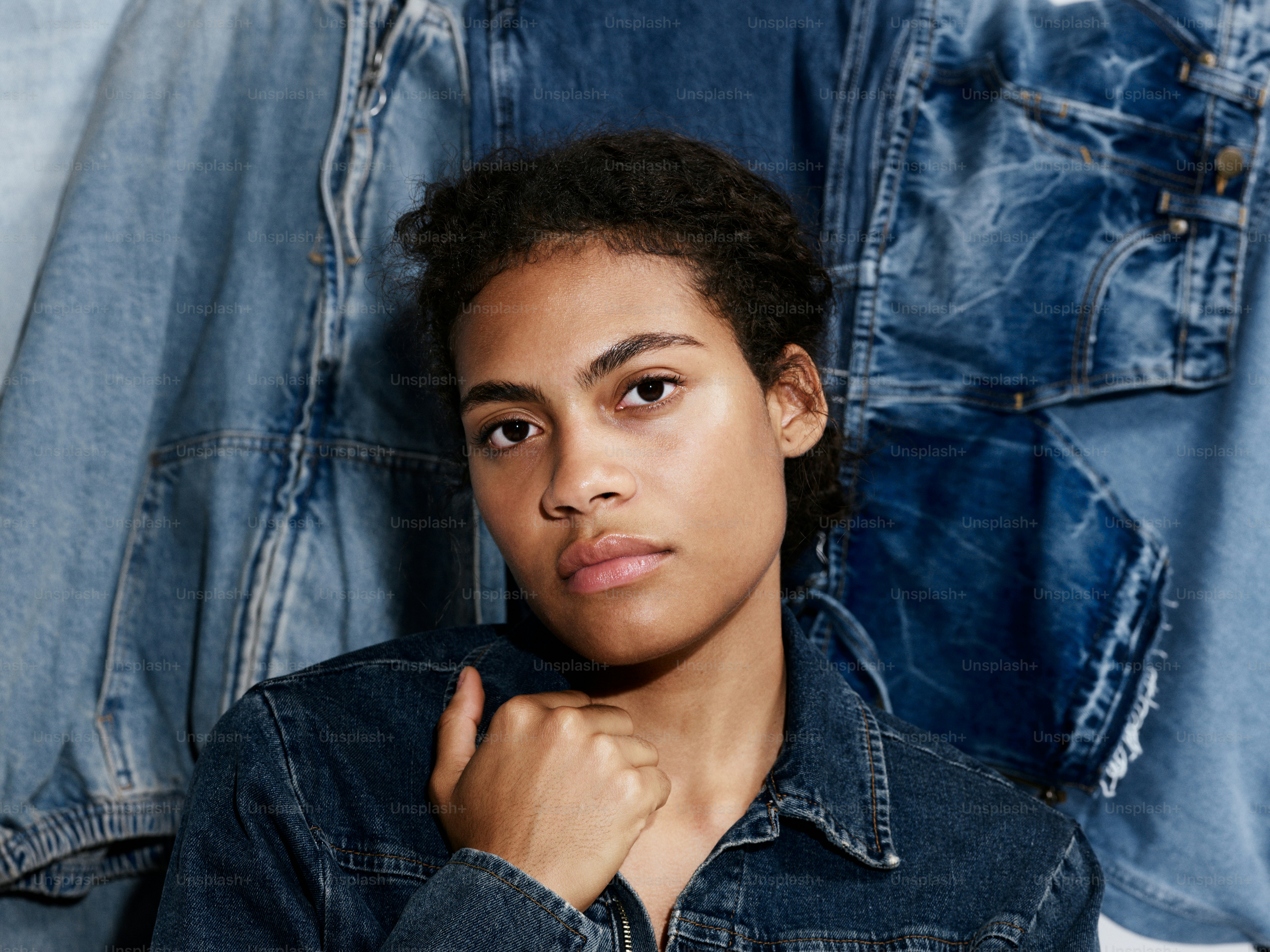 A young man standing in front of a pile of jeans