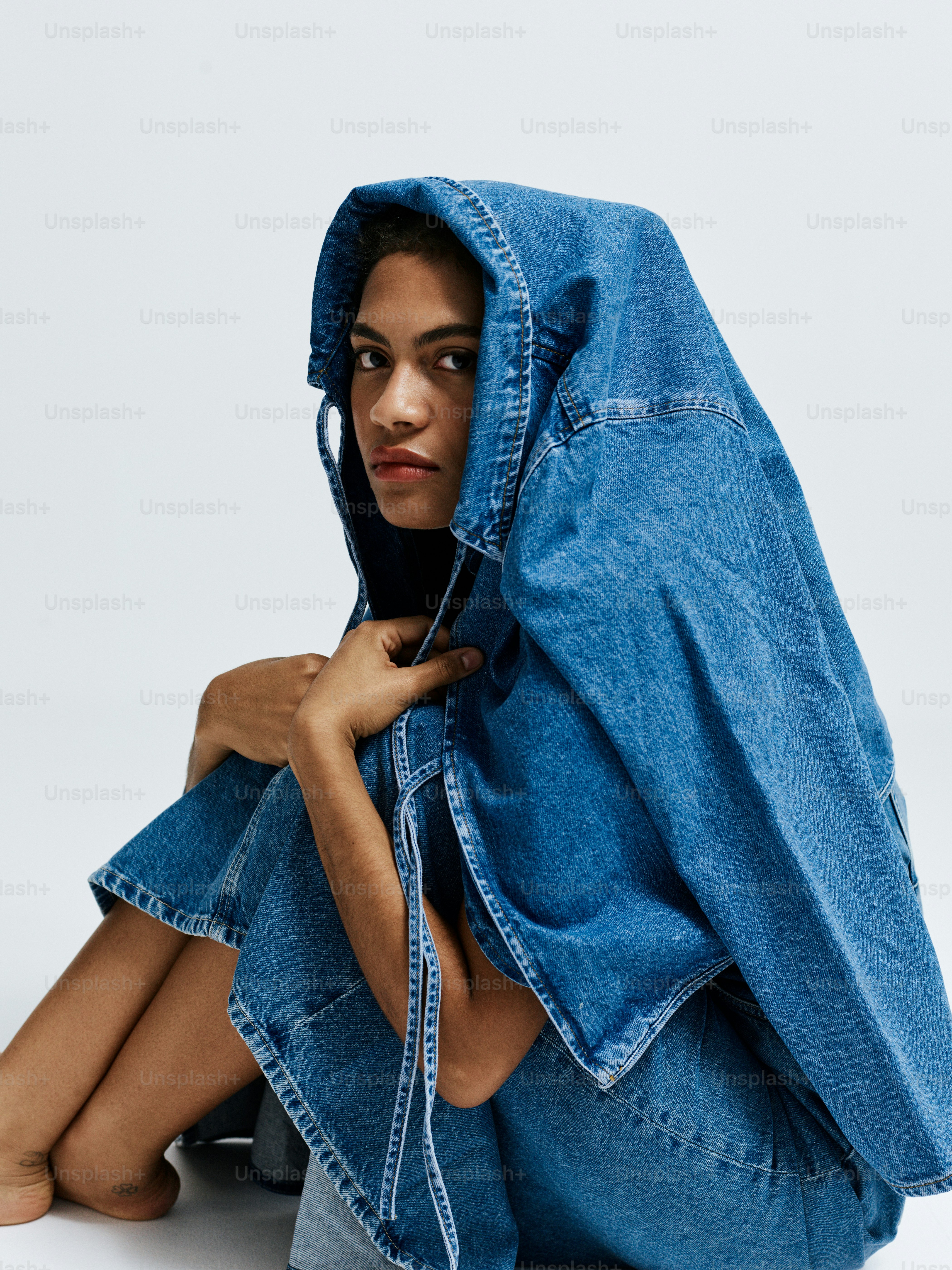 A woman sitting on the ground with a blue jacket over her head