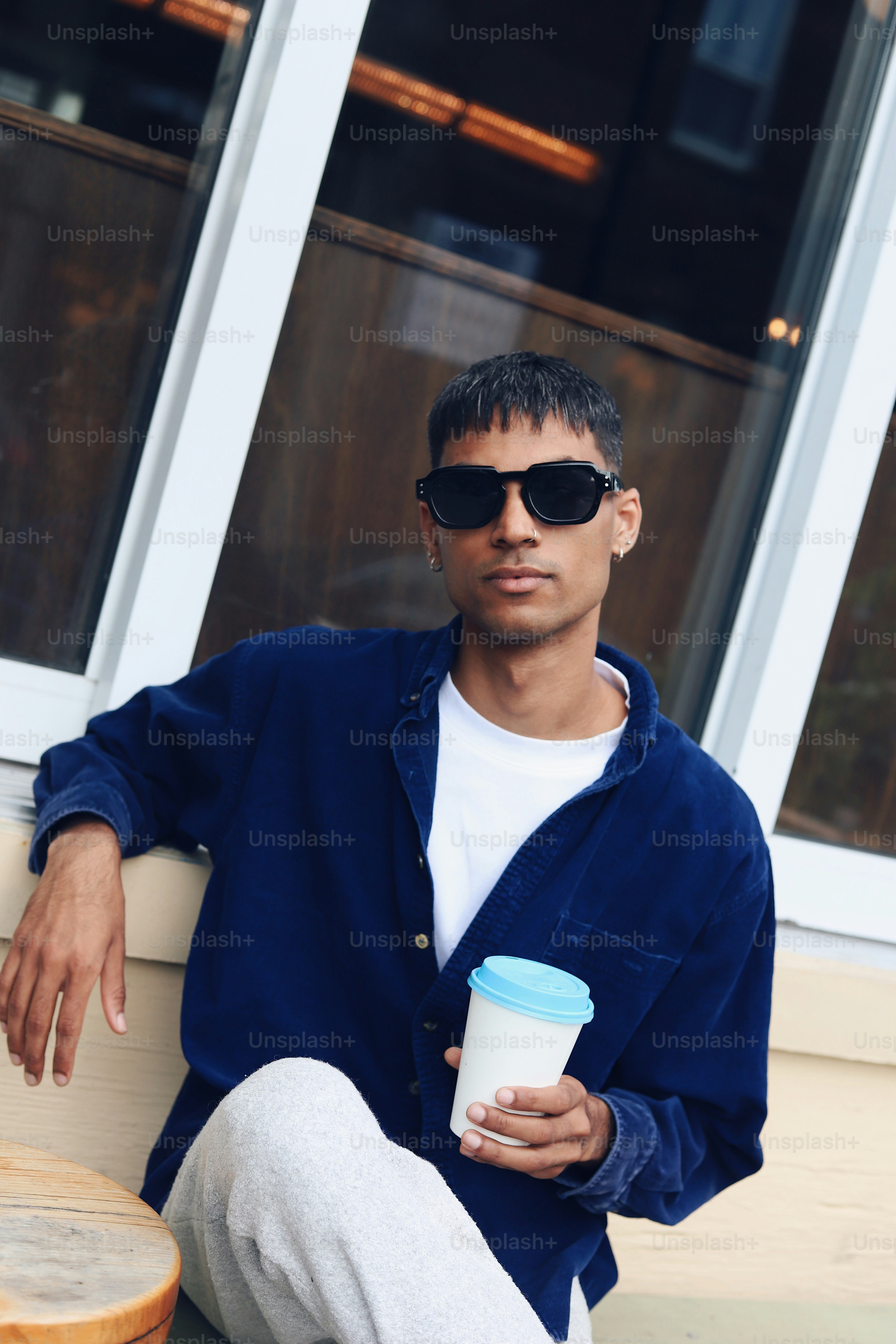 A man sitting on the ground holding a cup of coffee
