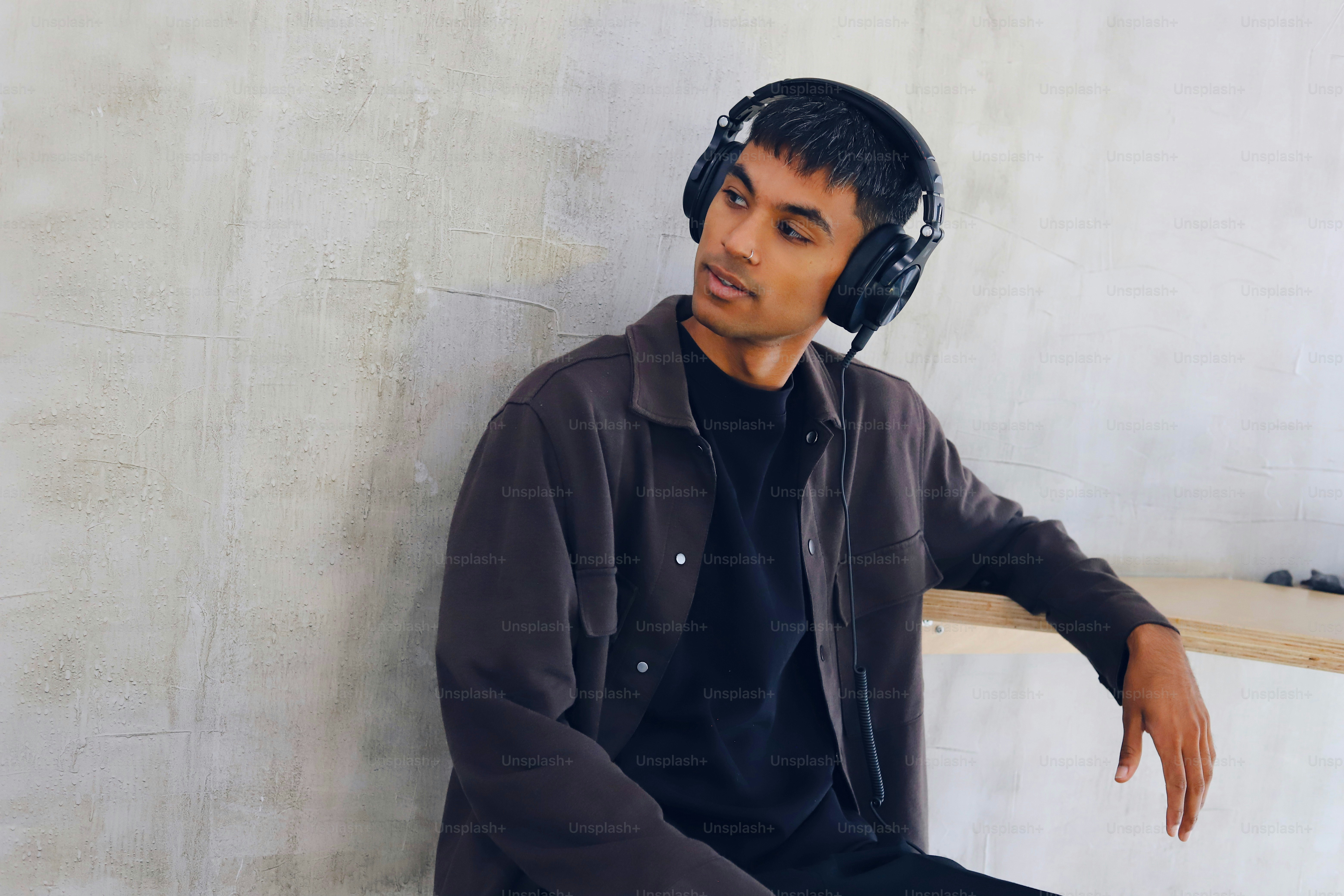 Seorang pria duduk di bangku mengenakan headphone