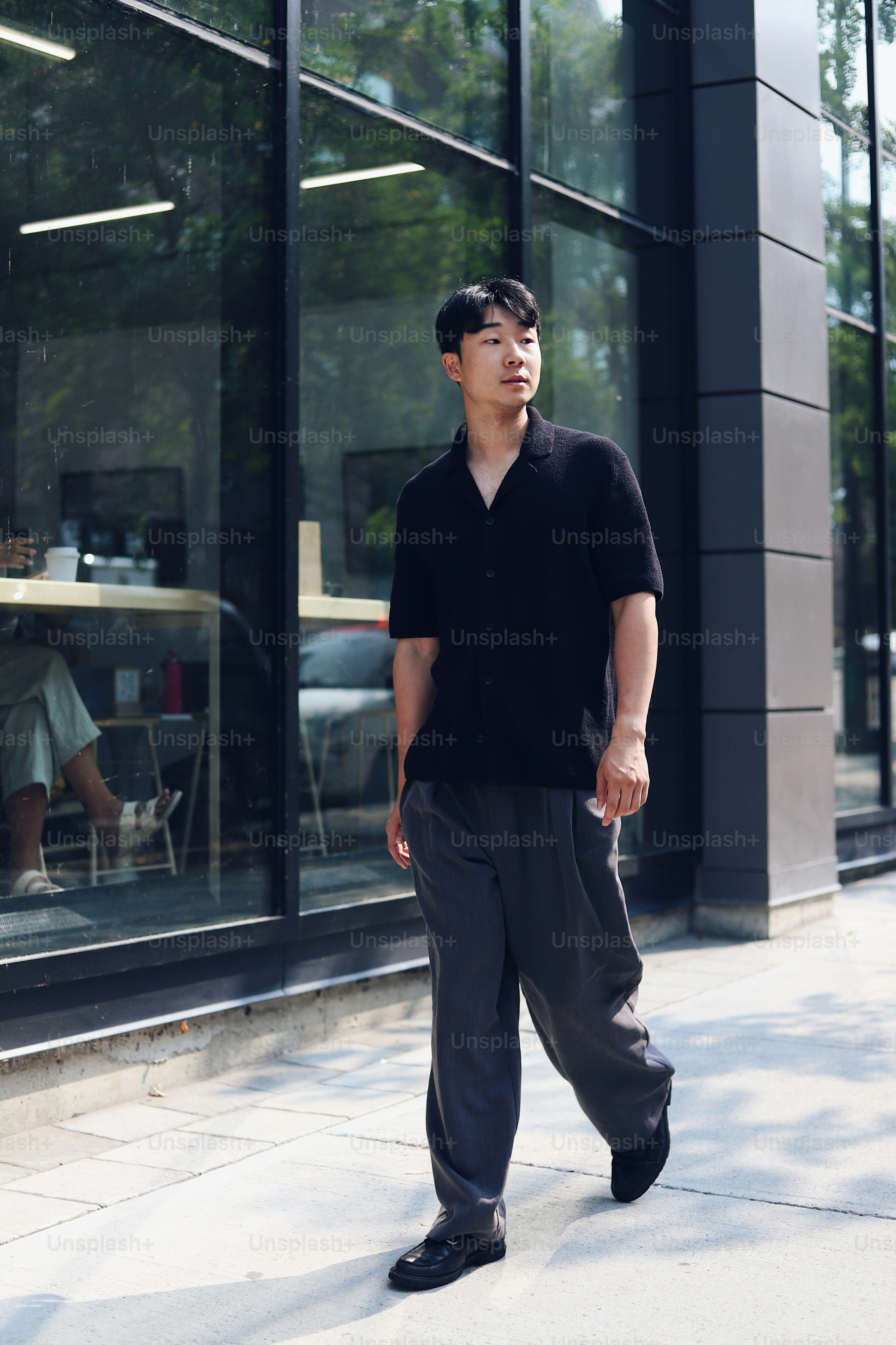 A man walking down a sidewalk next to a tall building photo  Walking Image  on Unsplash
