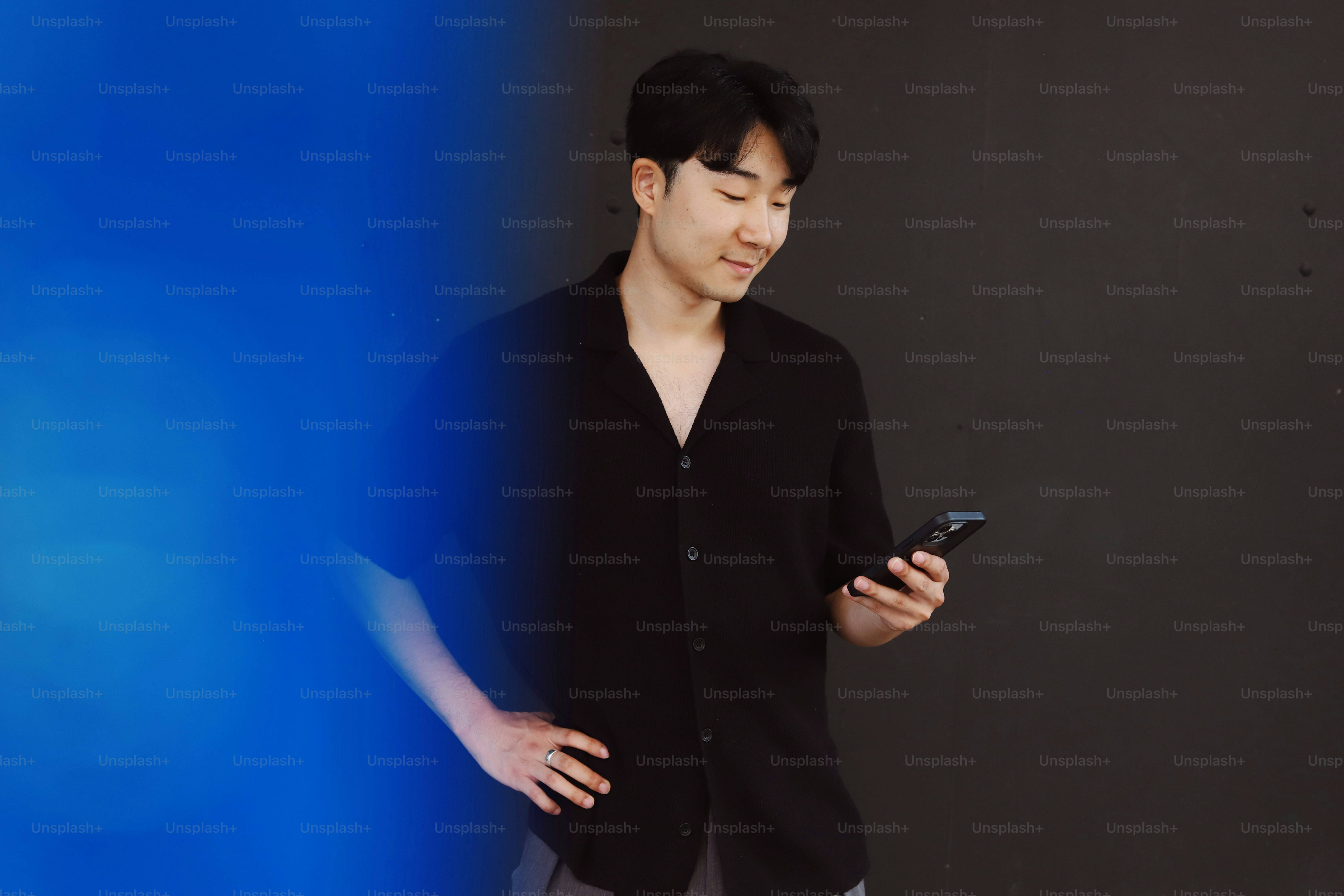 A man standing in front of a wall holding a cell phone