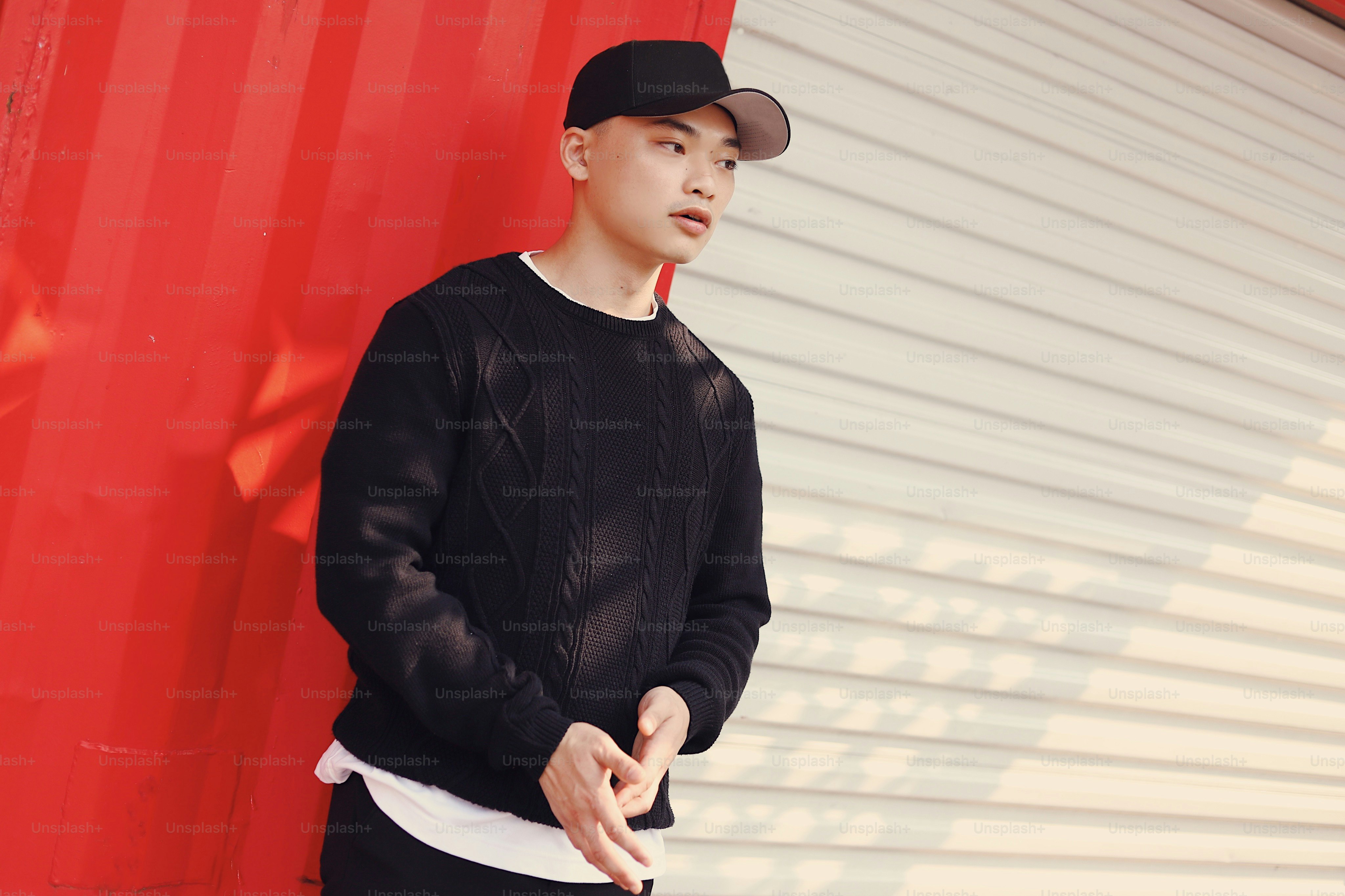 A young man standing in front of a red wall