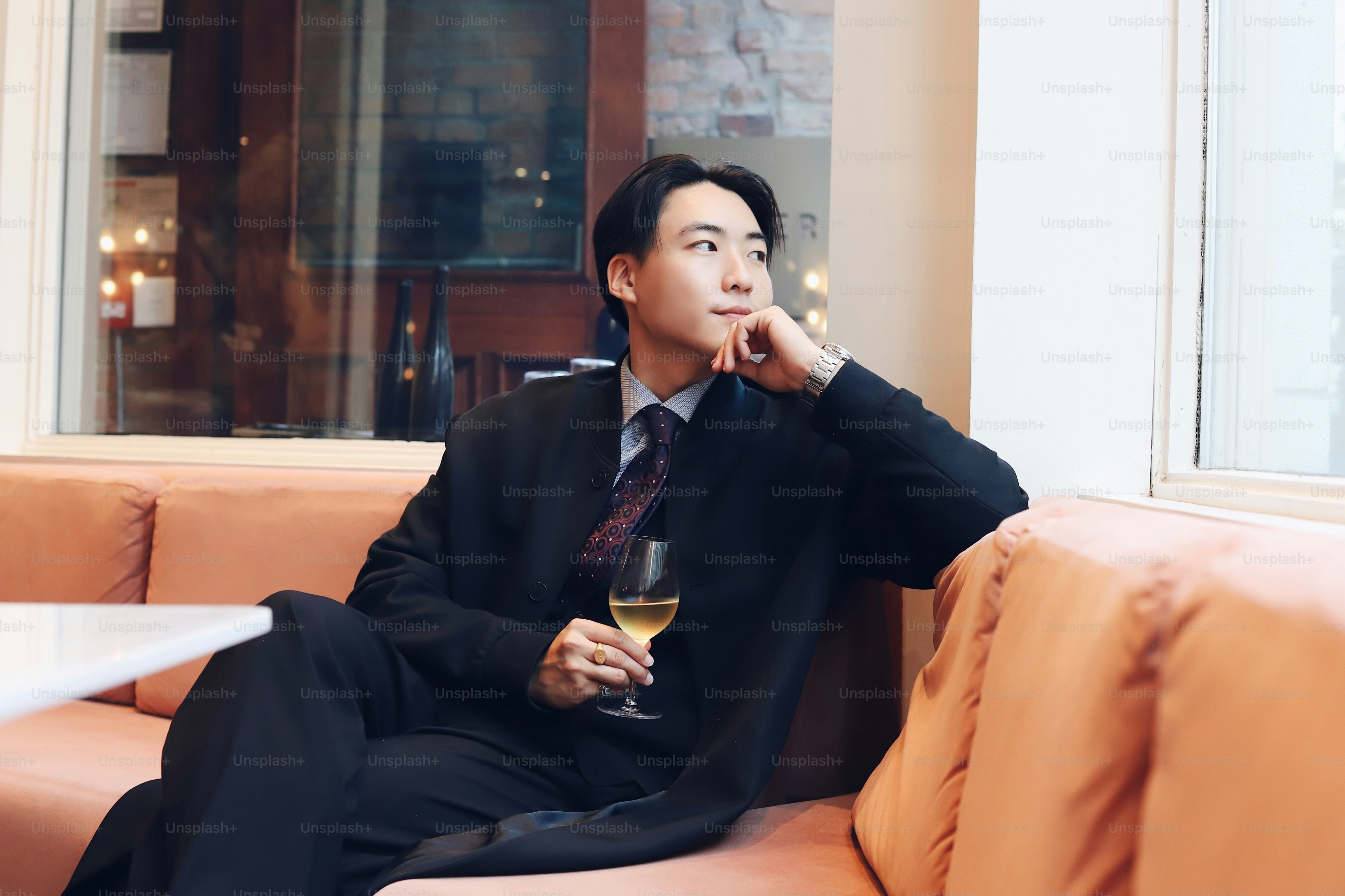 A man sitting on a couch with a glass of wine photo – Glass of wine ...