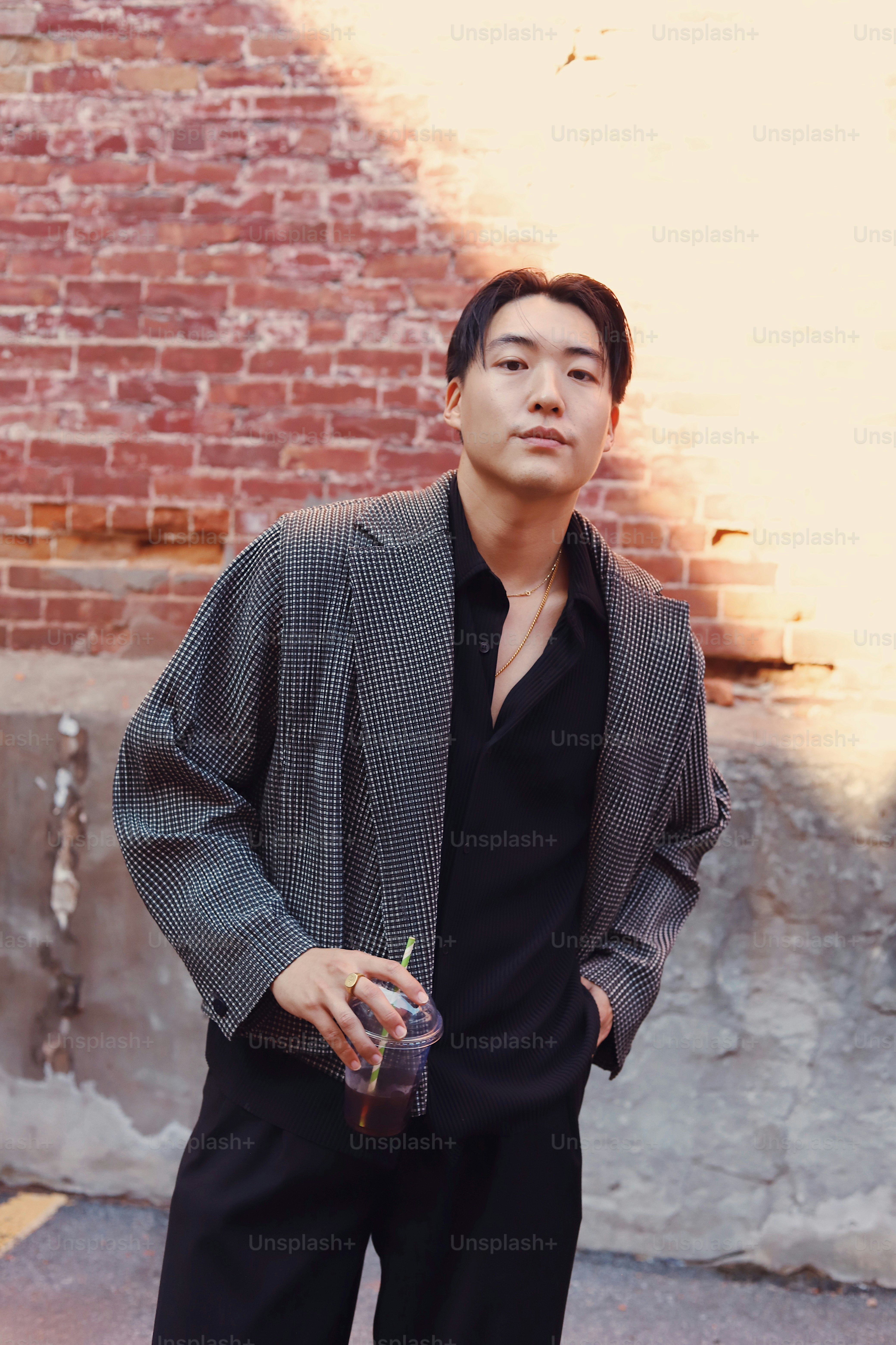 Un hombre de pie frente a una pared de ladrillos