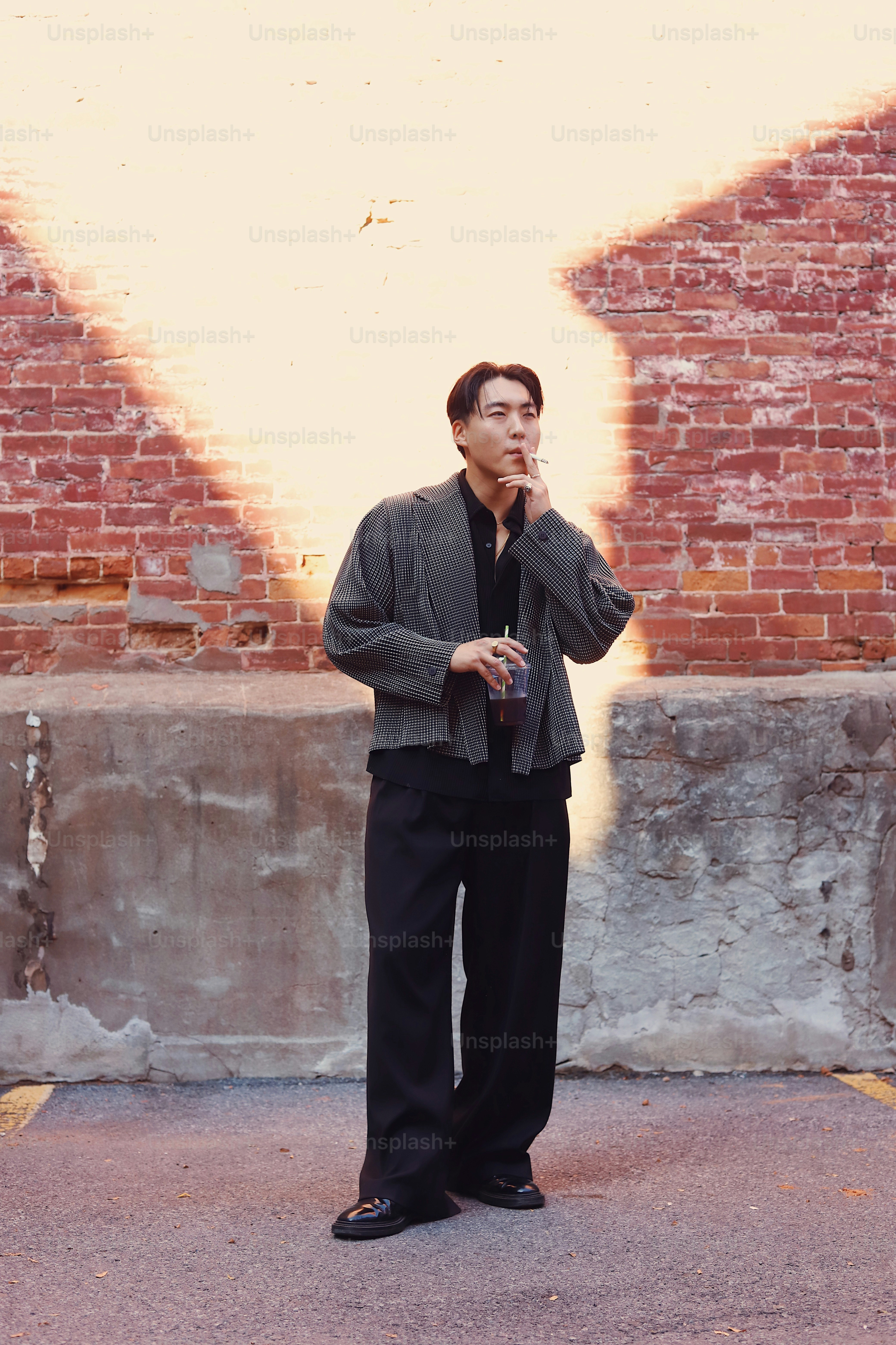 A man standing in front of a brick wall talking on a cell phone