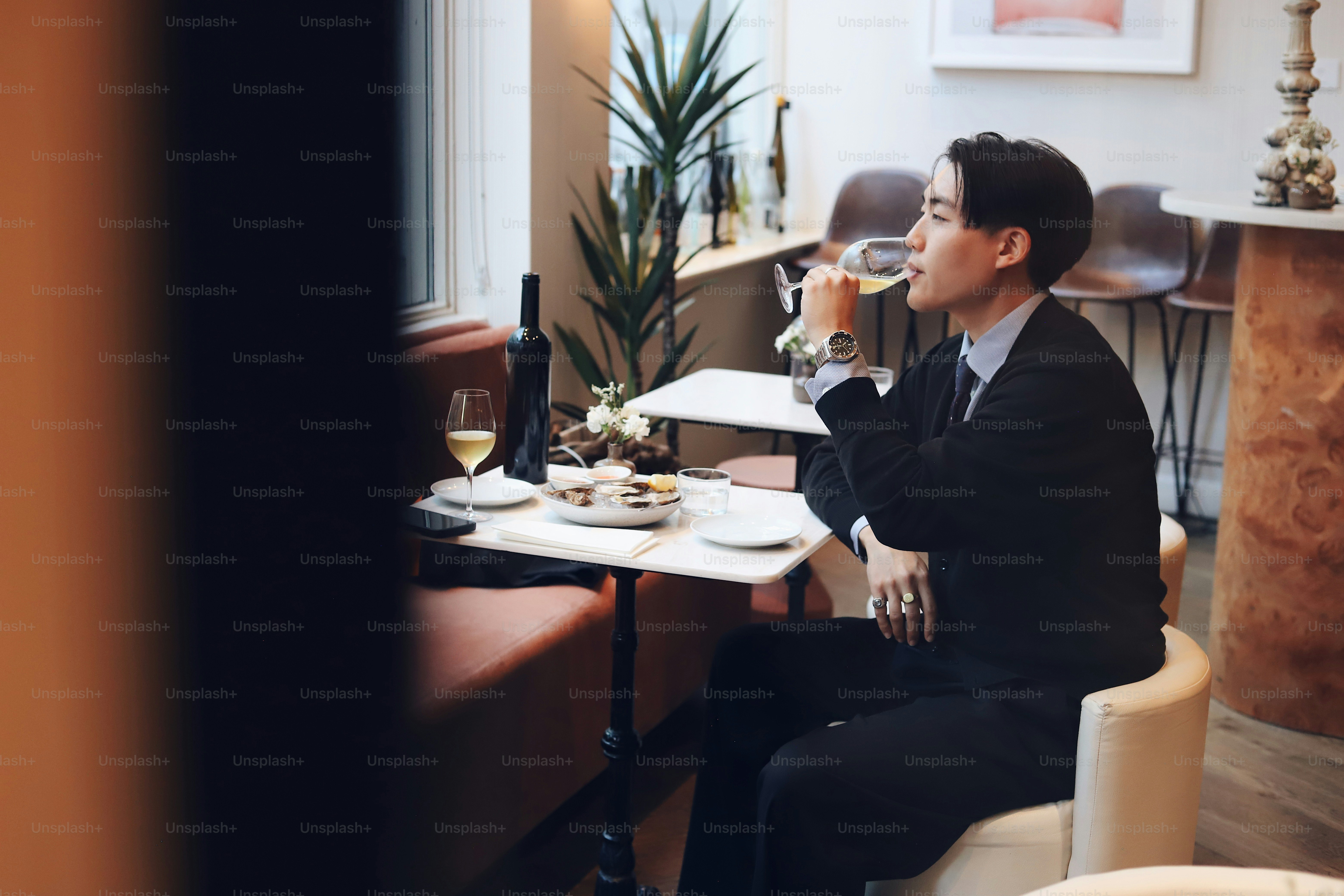 A man sitting at a table drinking a glass of wine