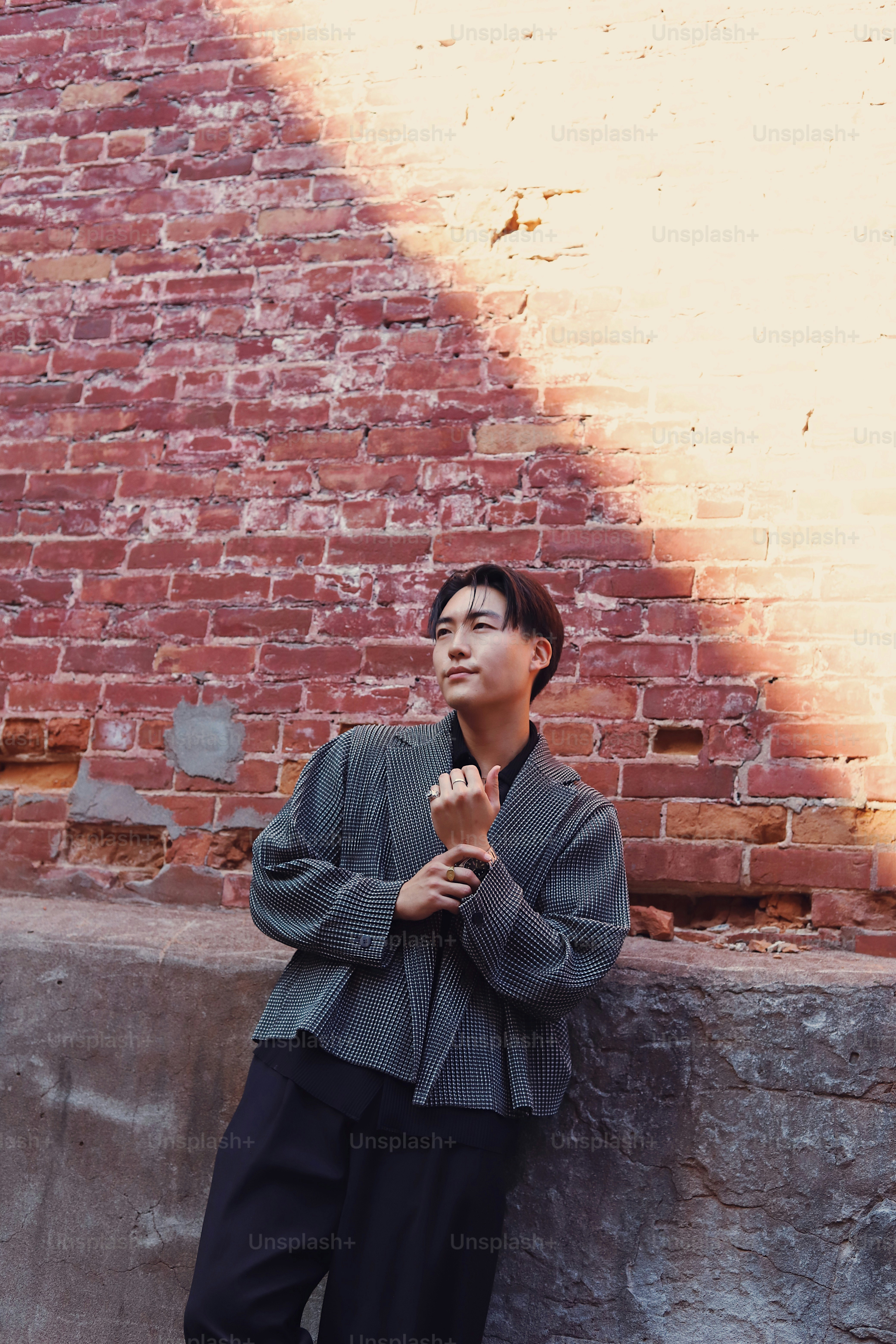 A man standing in front of a brick wall photo – Handsome man Image on ...