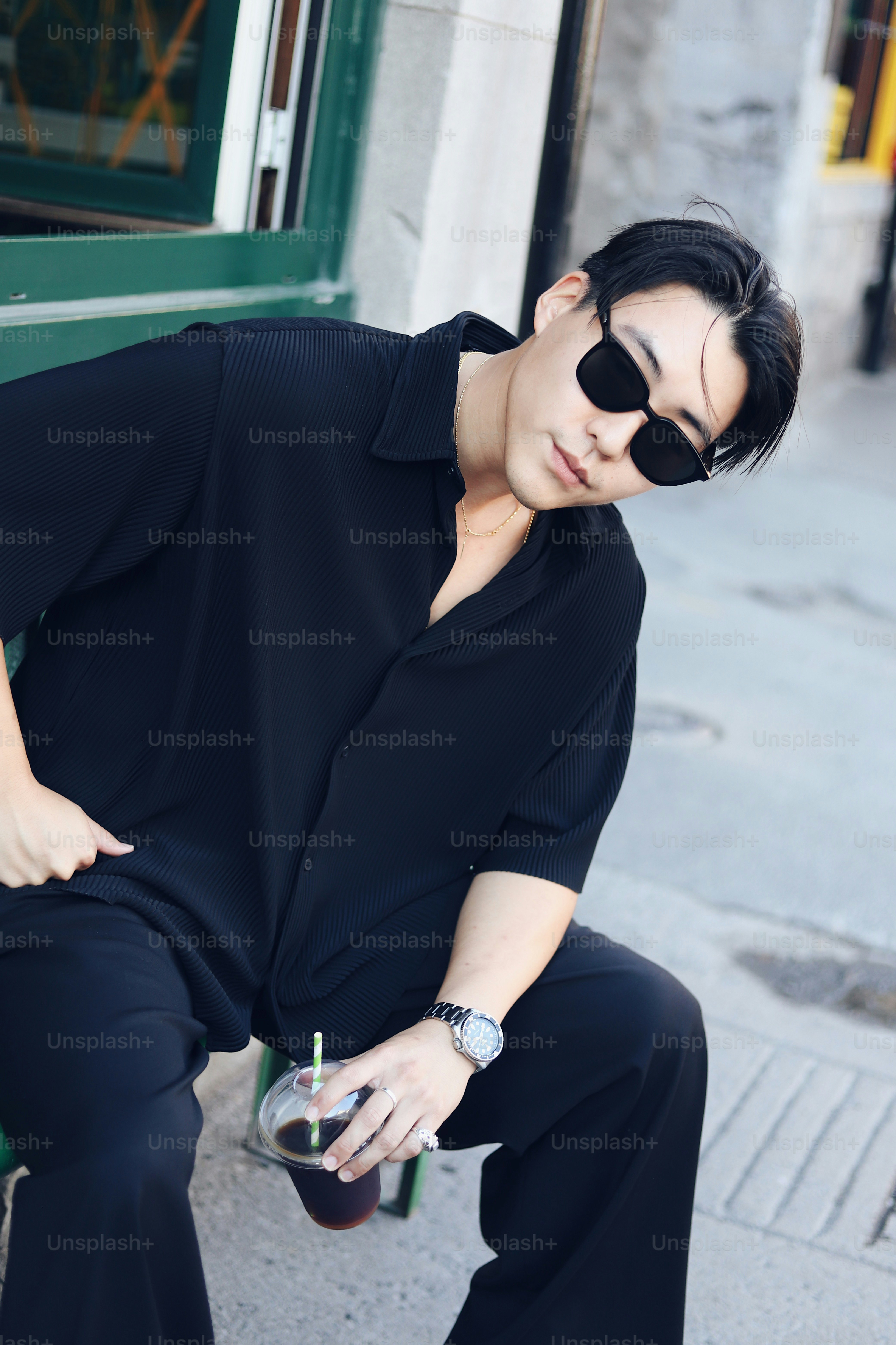 A man in a black shirt and black pants sitting on a green bench