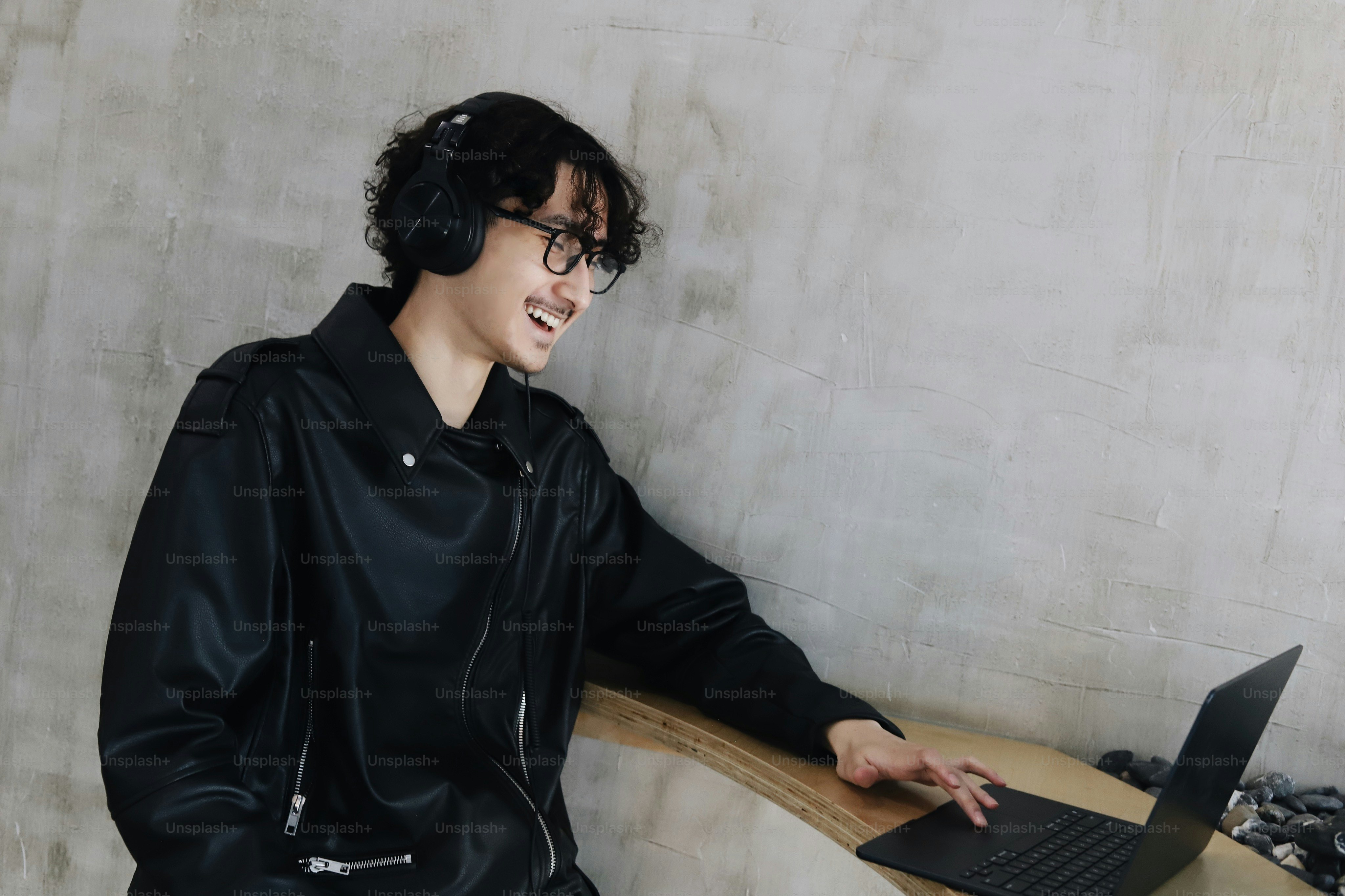 A man in a black jacket is using a laptop