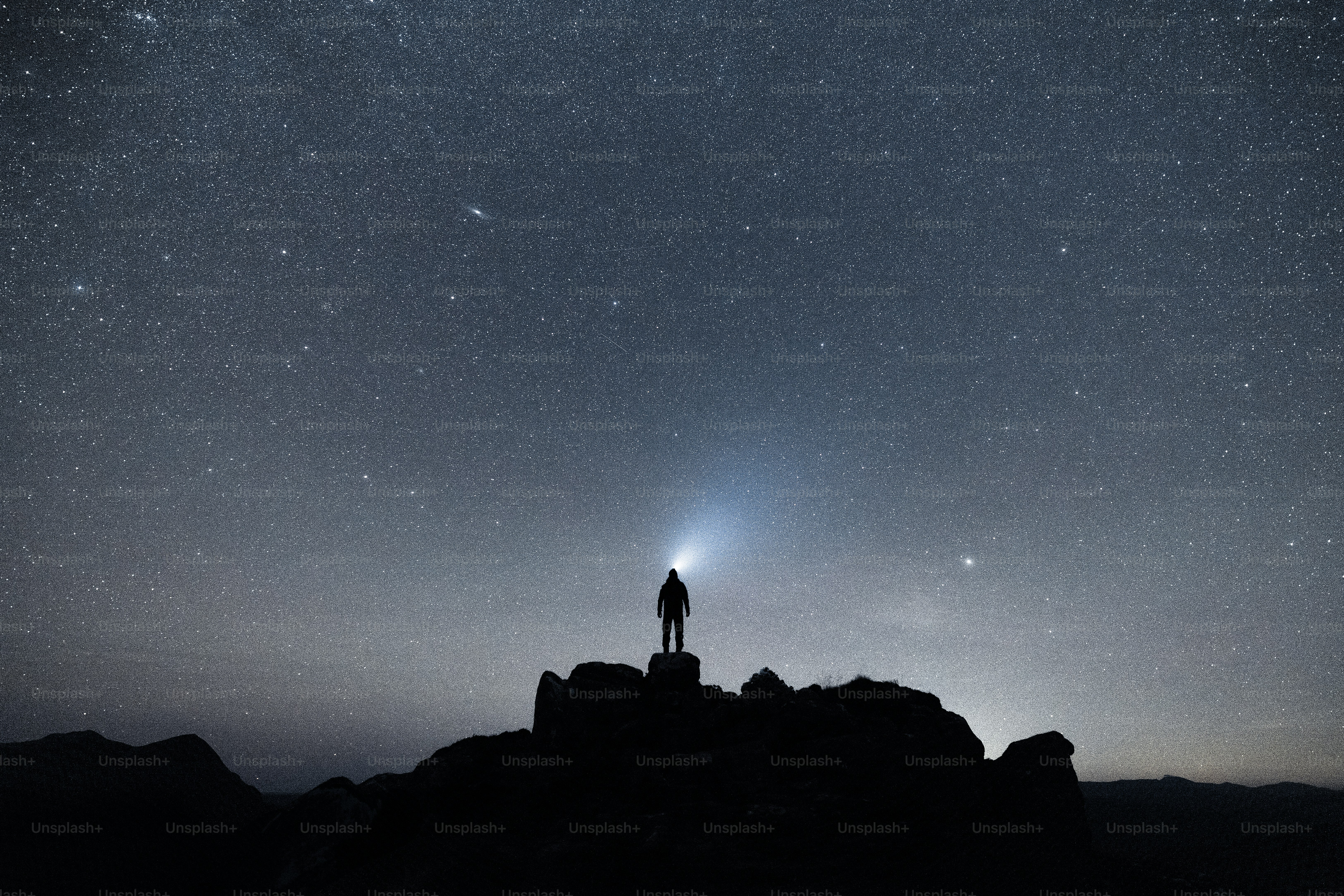 A person standing on top of a mountain under a star filled sky