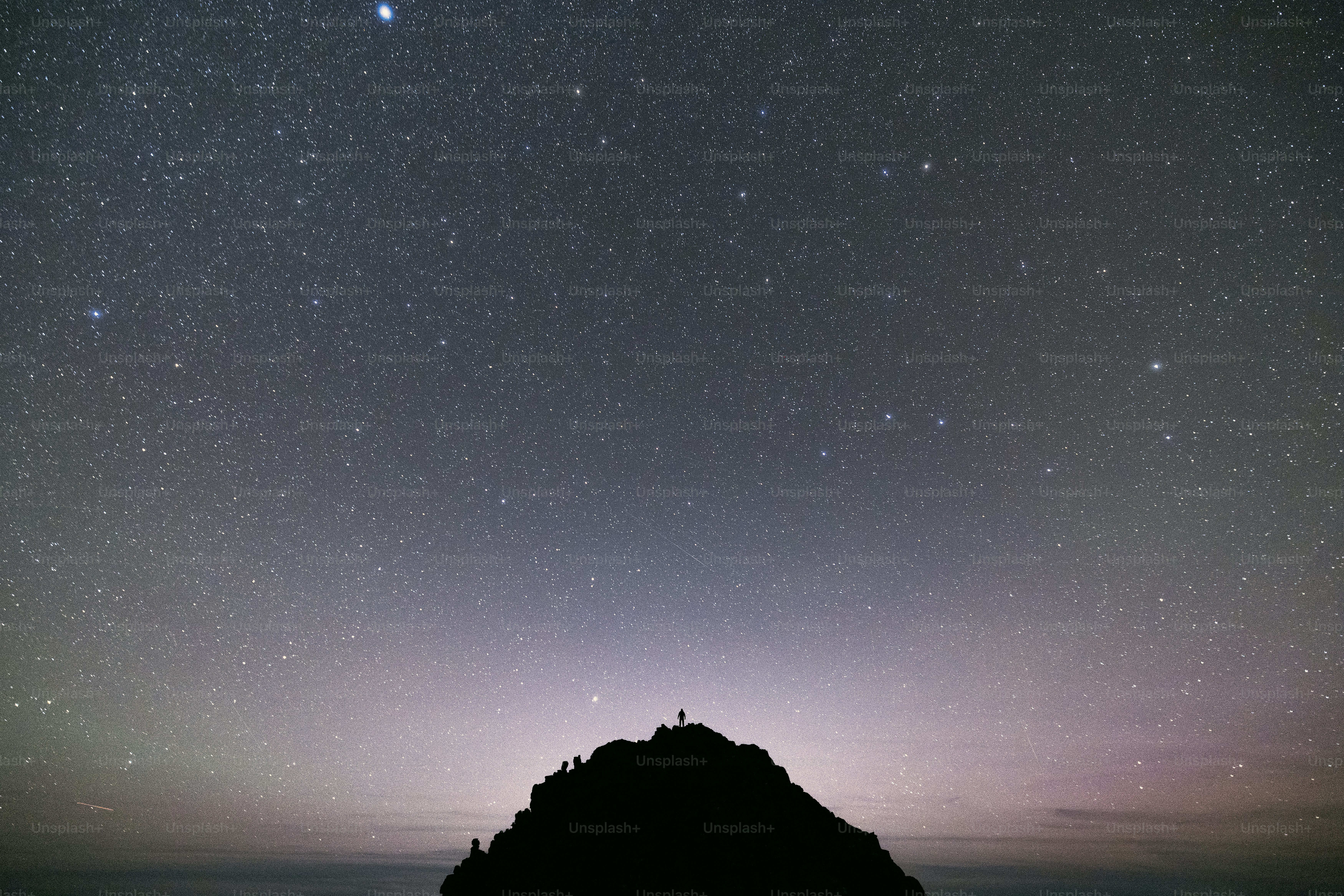 The night sky with stars above a mountain