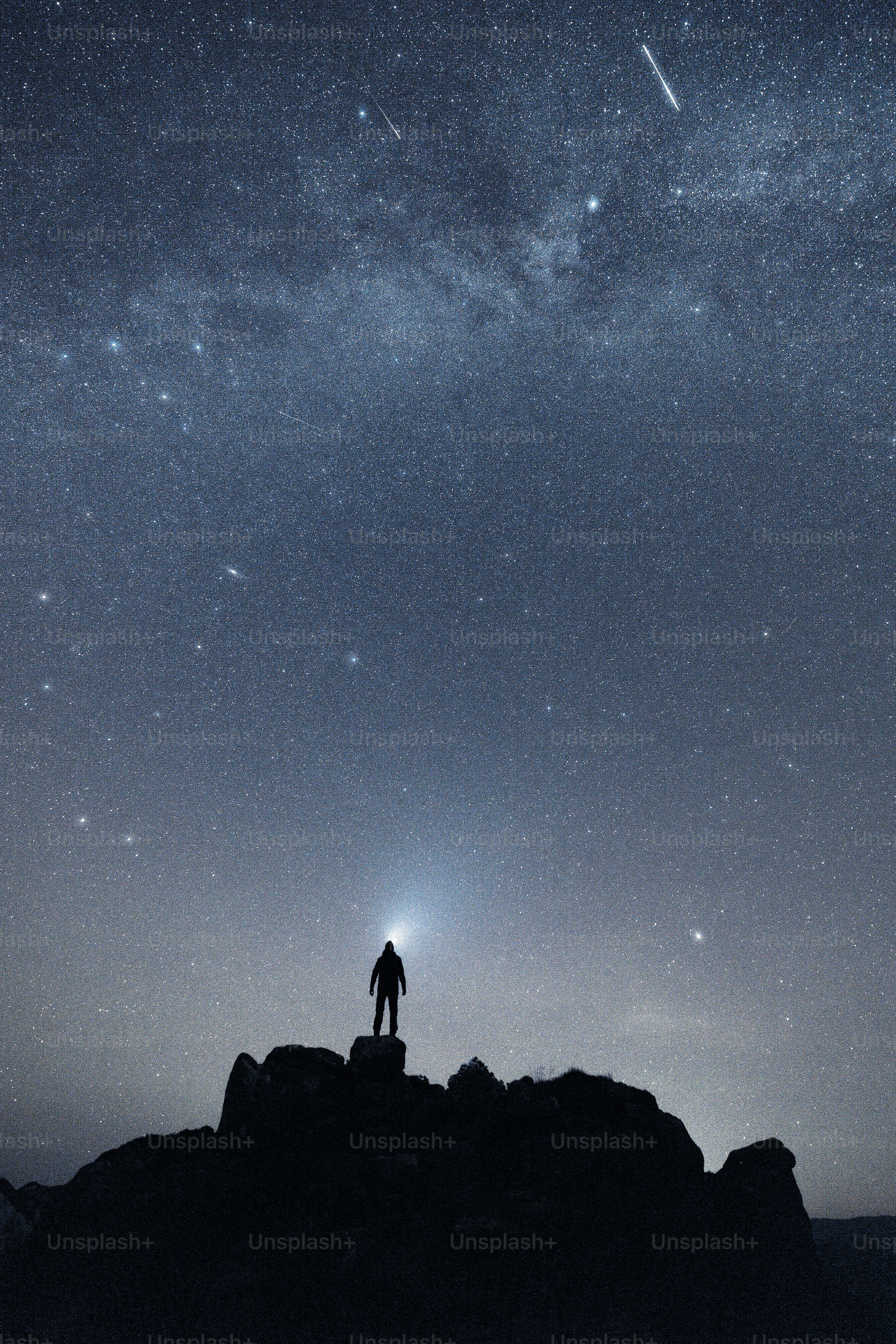 A man standing on top of a rock under a night sky filled with stars