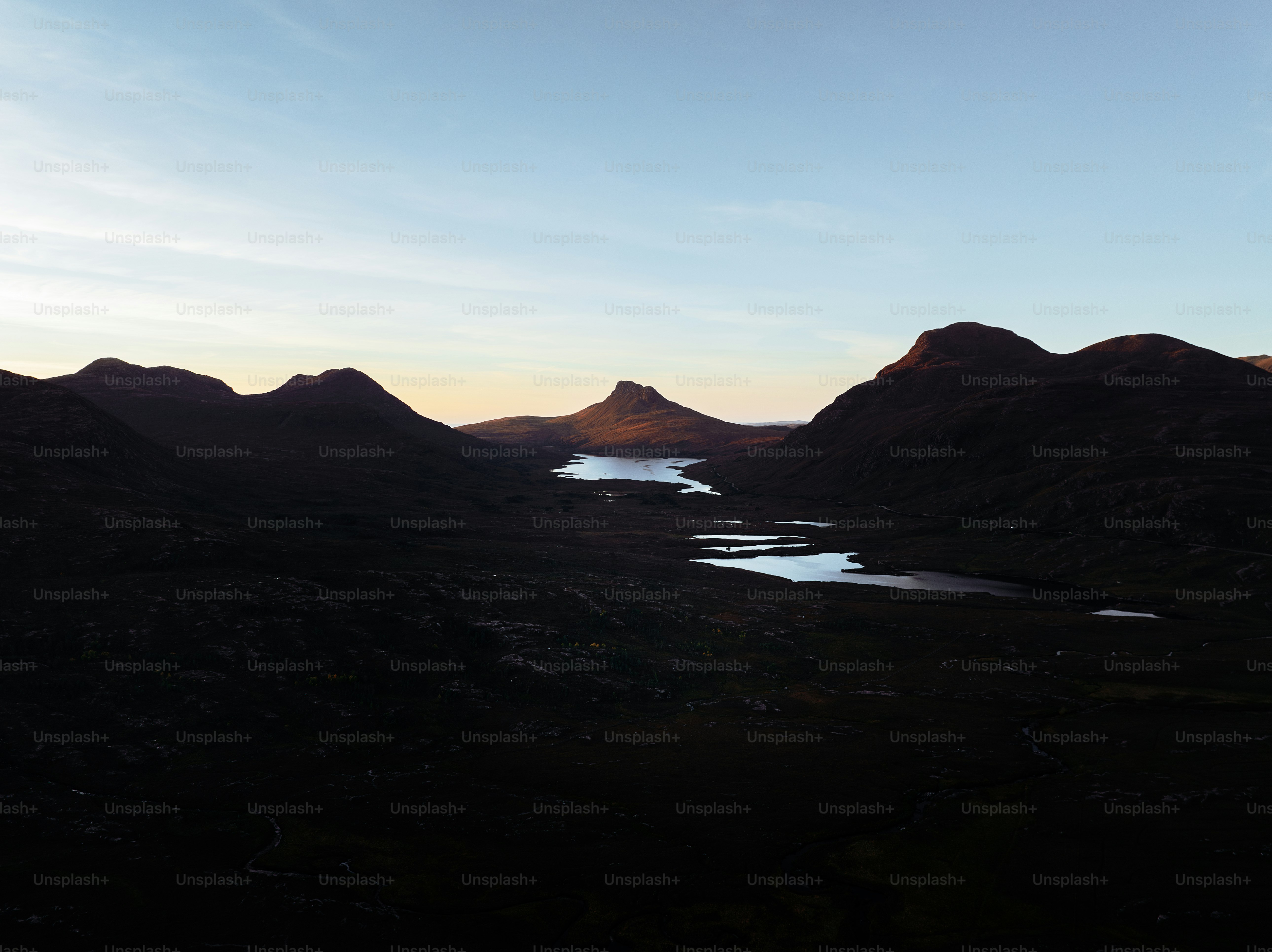 A sunset view of a mountain range with a lake in the foreground photo ...
