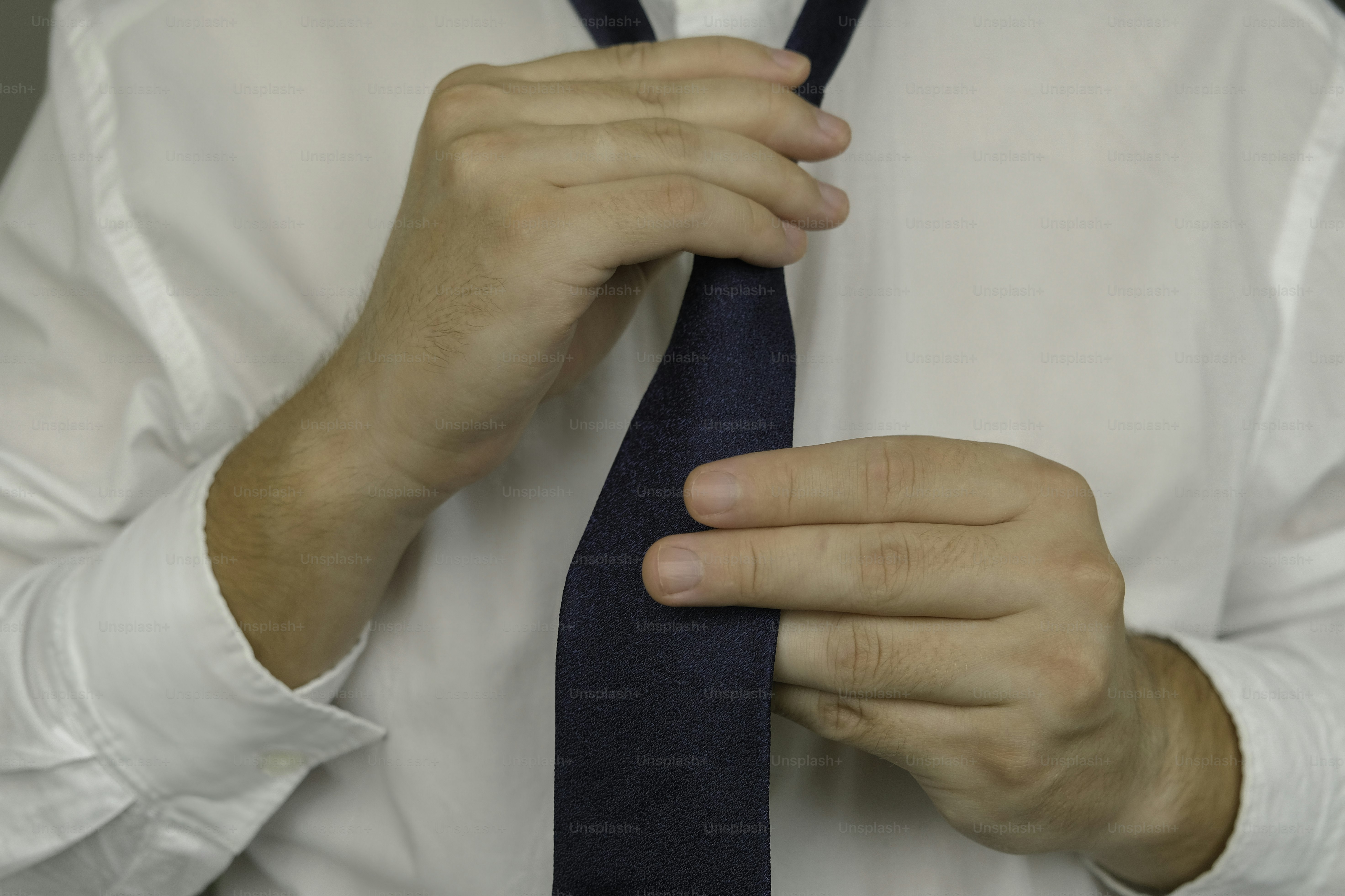 A man in a white shirt tying a blue tie