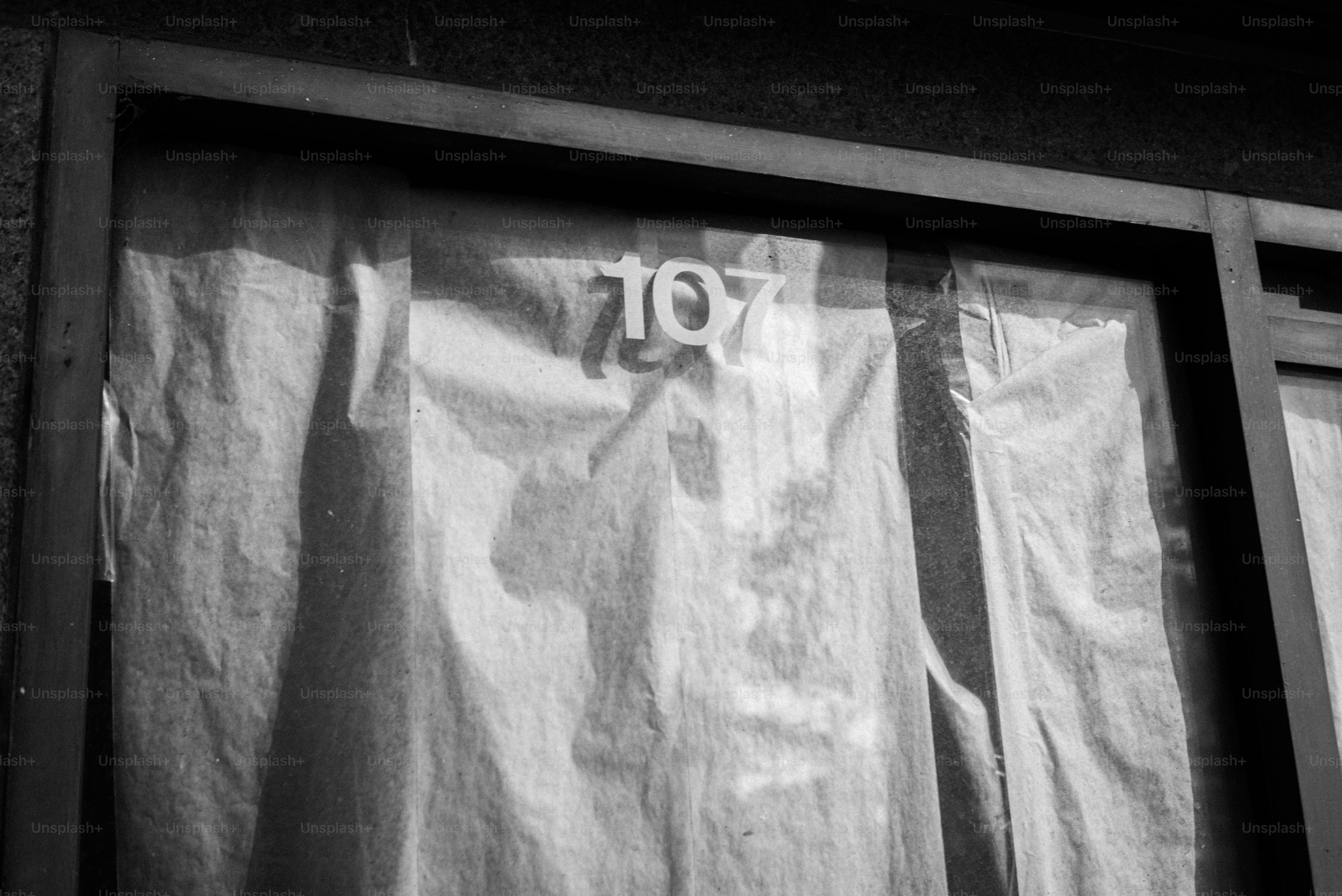 A black and white photo of a curtained window