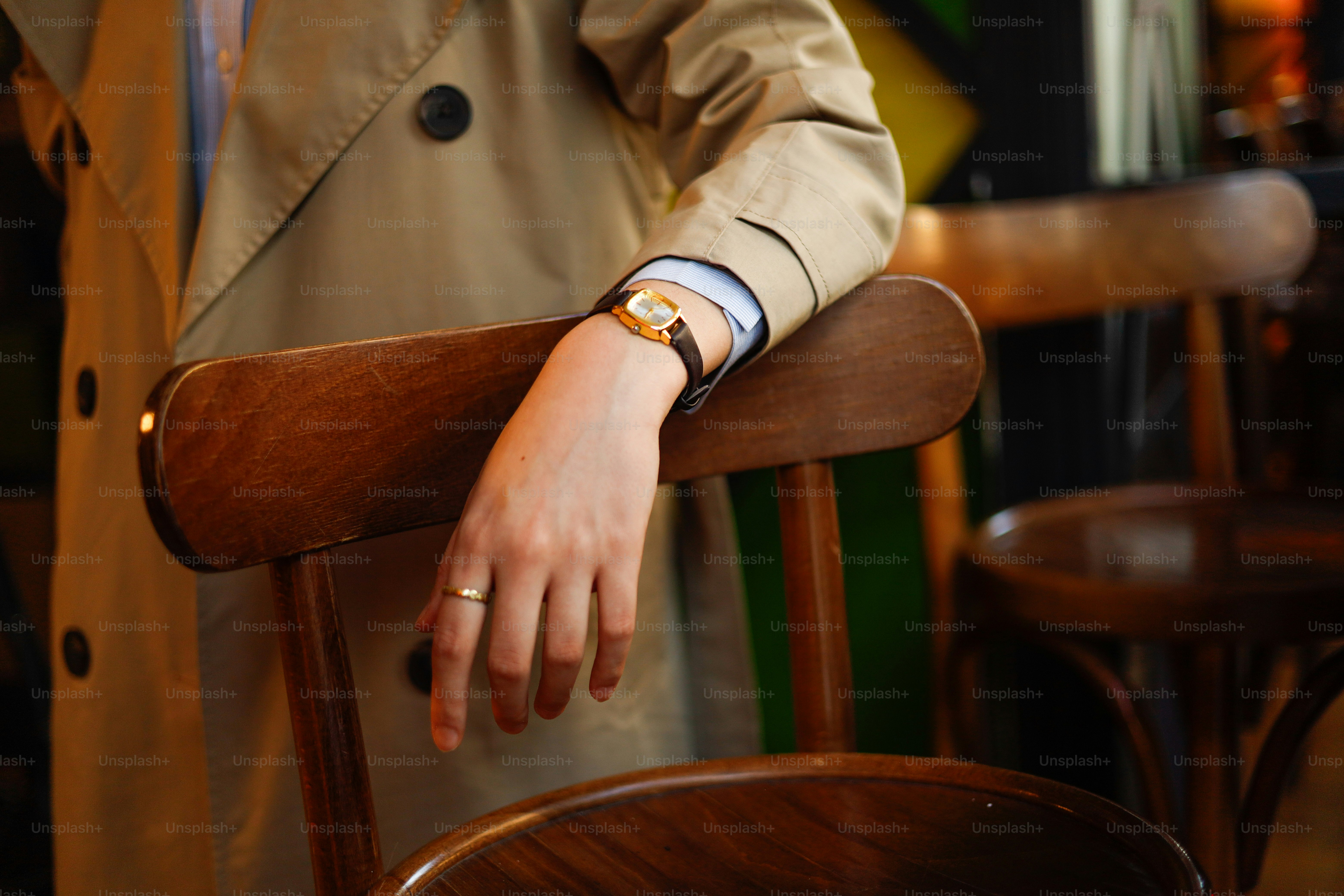 A man in a trench coat leaning on a chair