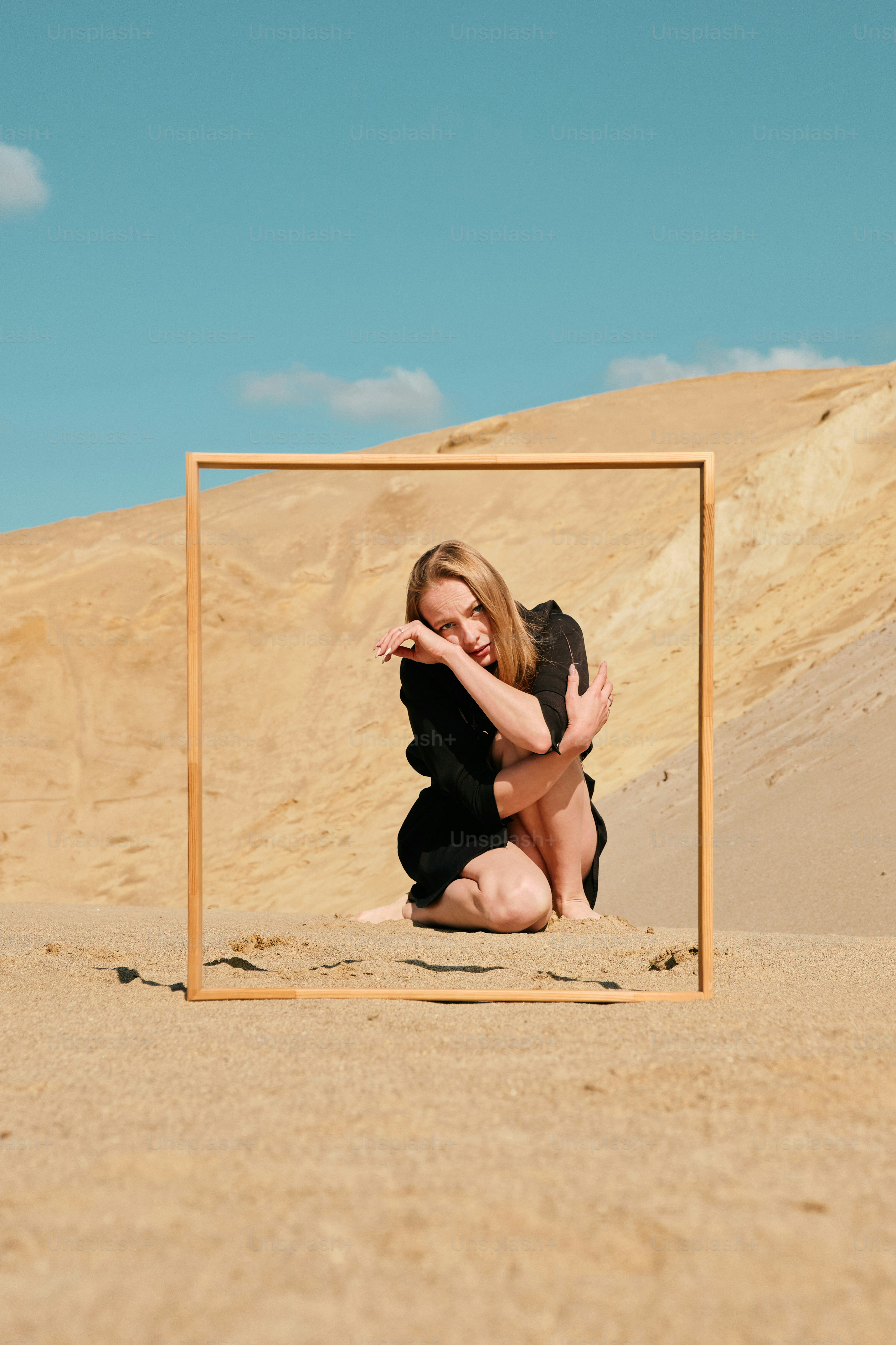 A woman sitting on the ground in front of a picture frame