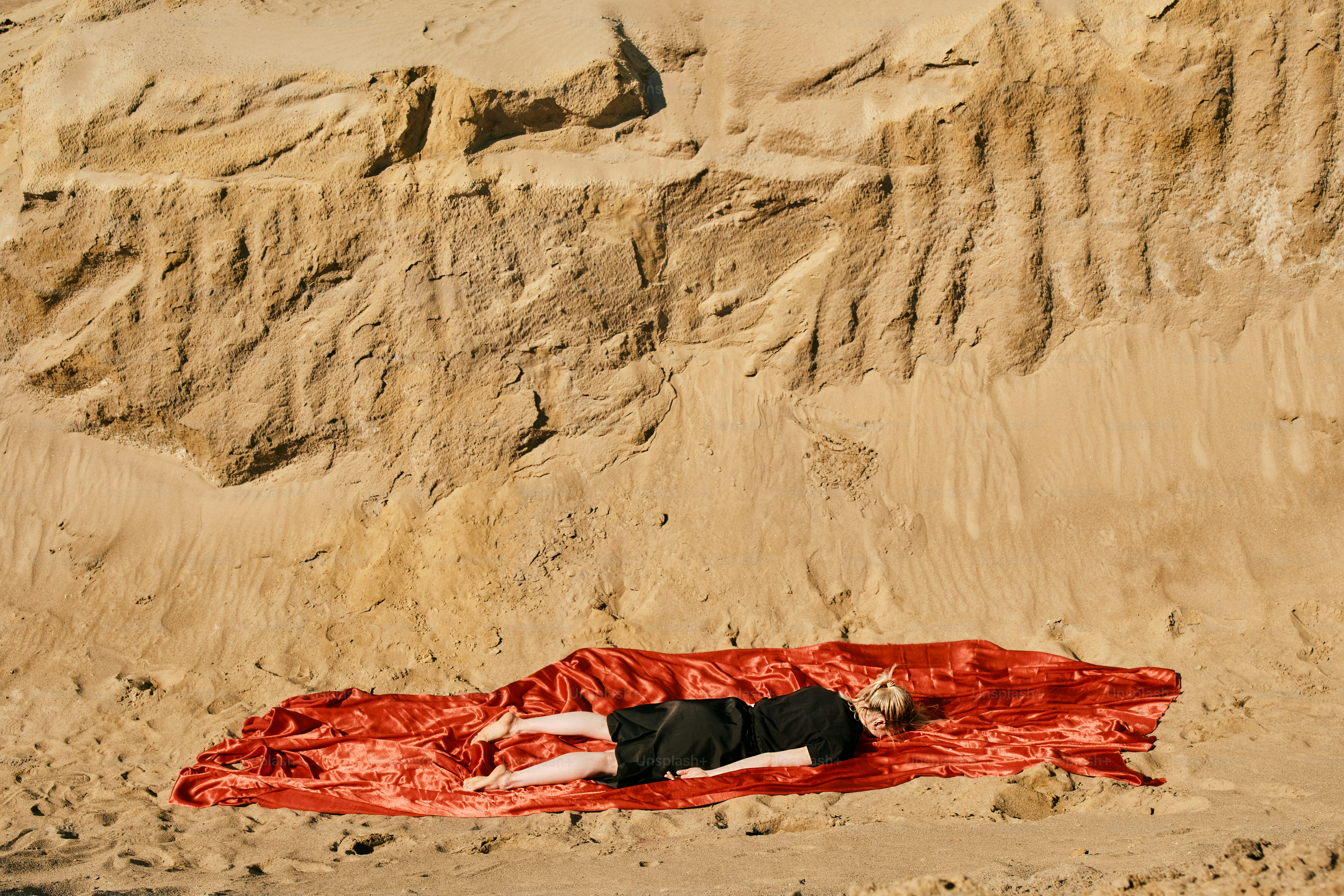 A person laying on a blanket in the sand
