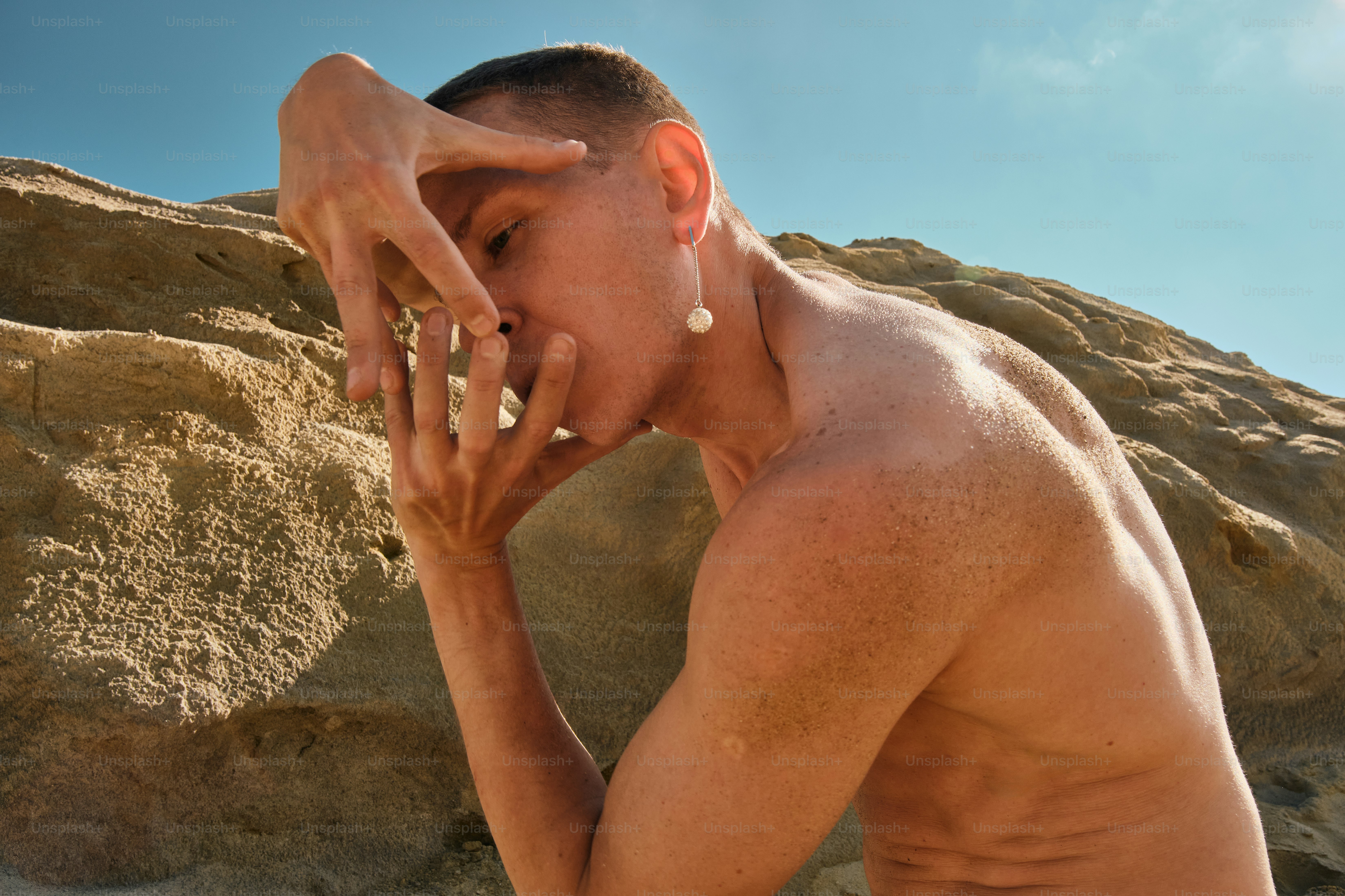 A shirtless man standing in front of a mountain