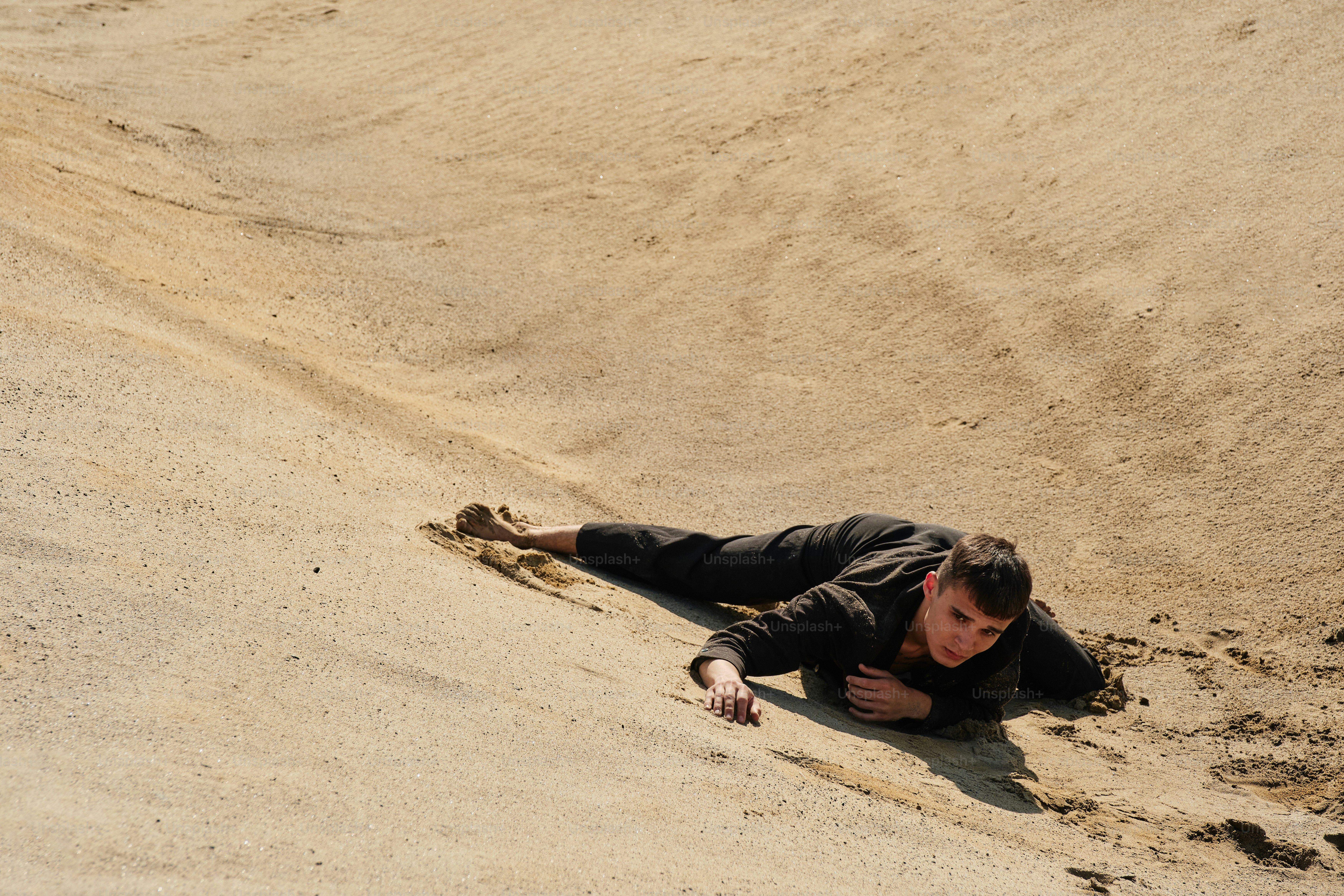 A man laying on top of a sandy beach