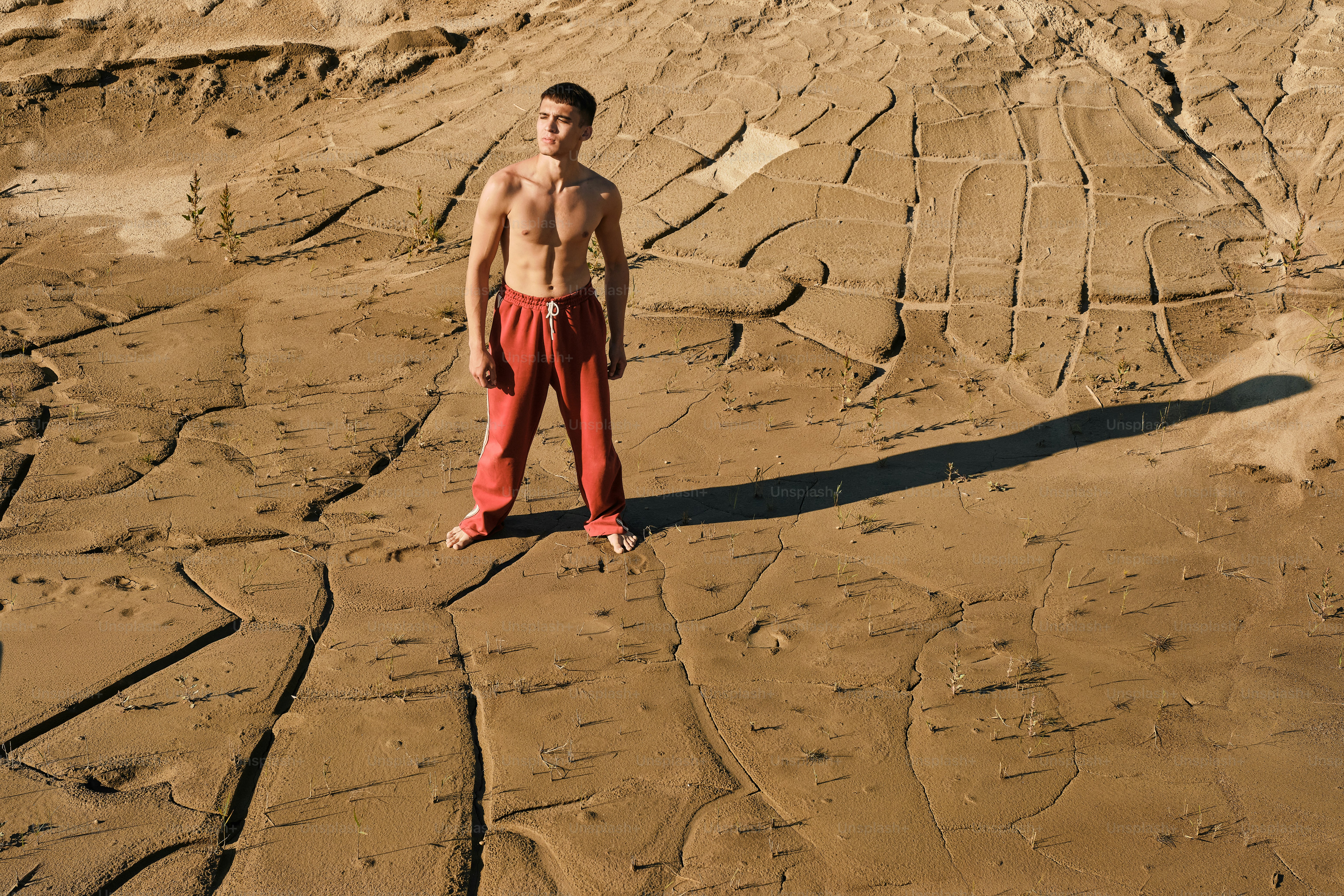 A person kneeling in the sand with a picture frame in front of them ...