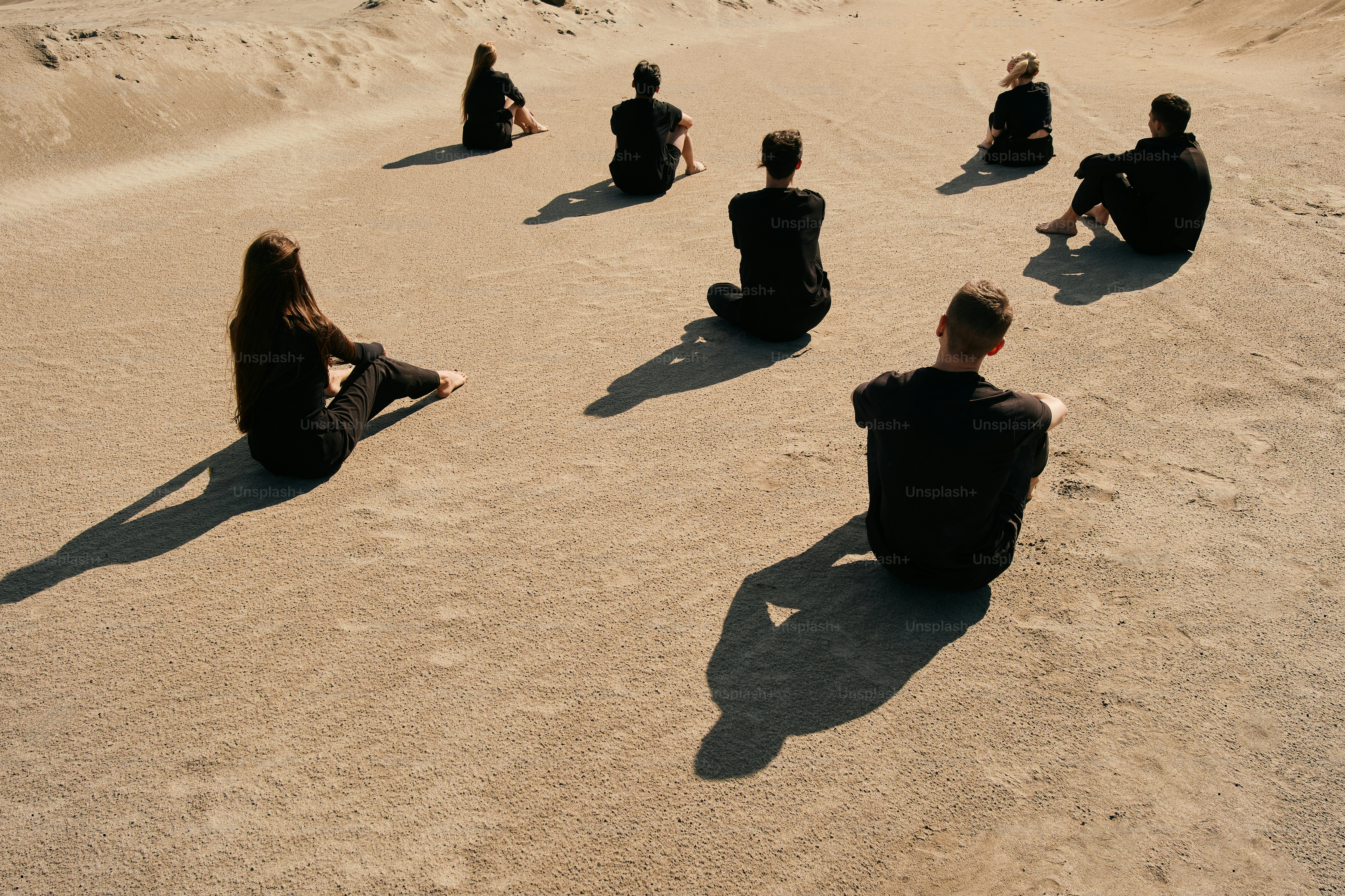 A group of people sitting on top of a sandy beach