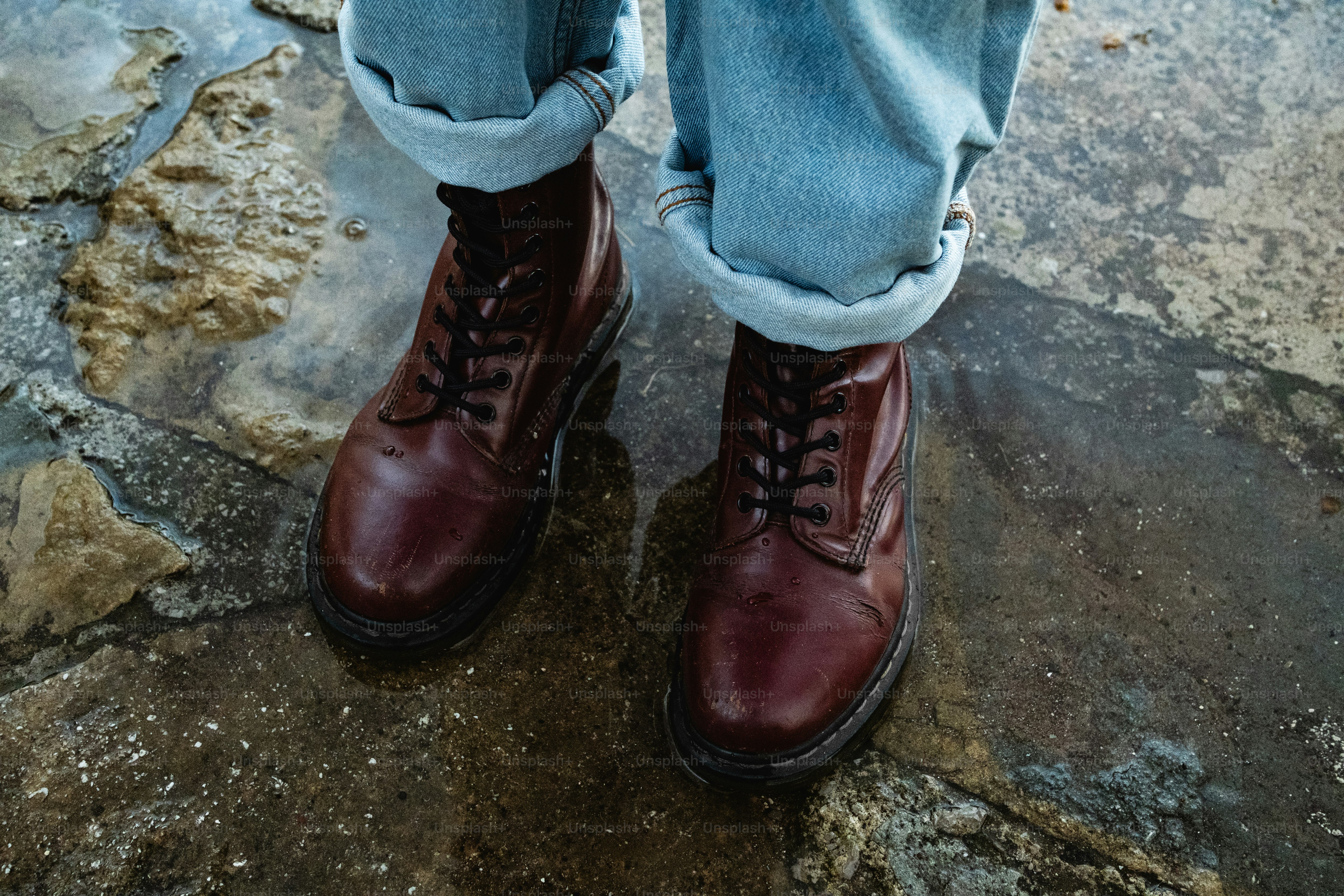 A person wearing blue jeans and brown boots