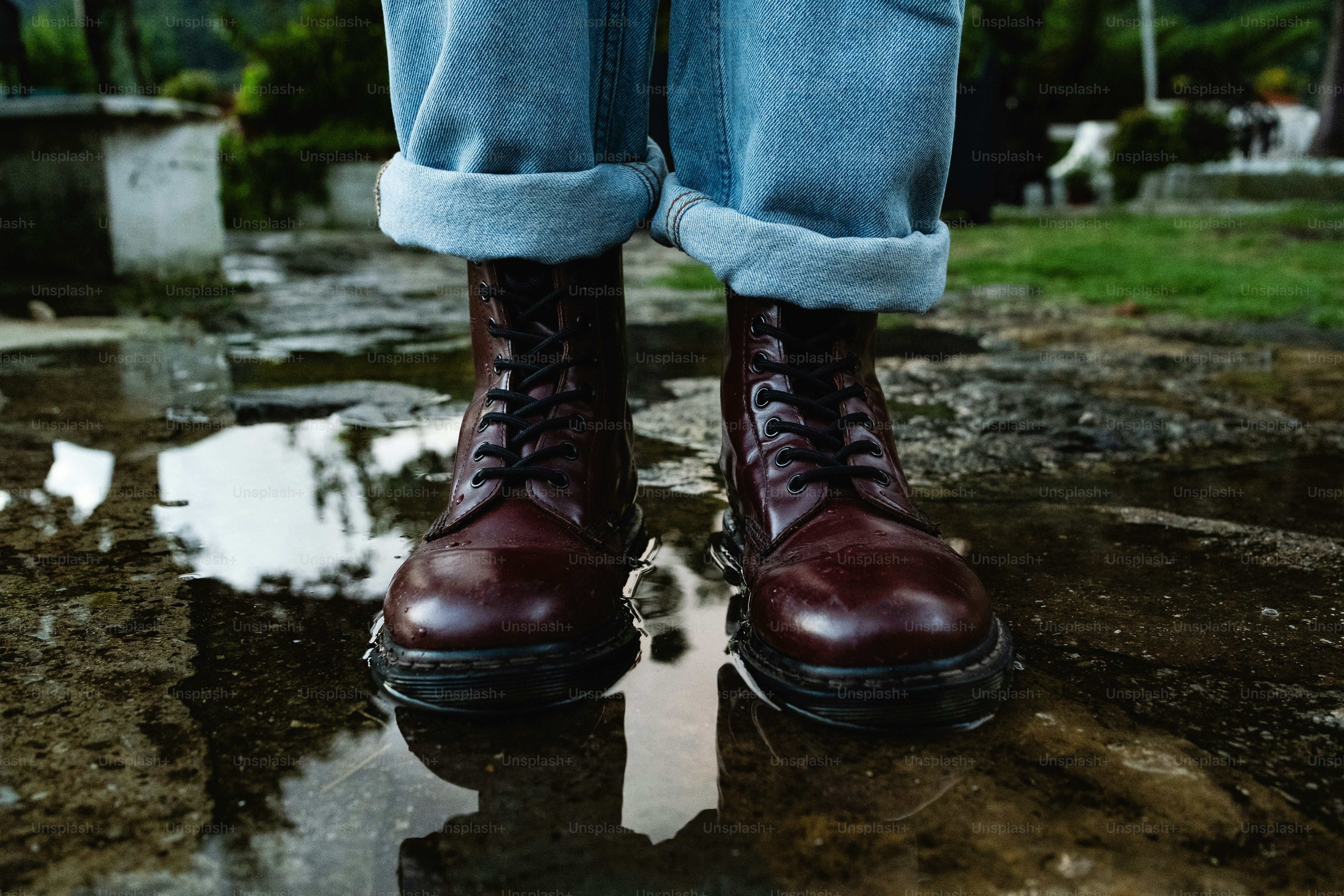 A person standing in the rain wearing red boots