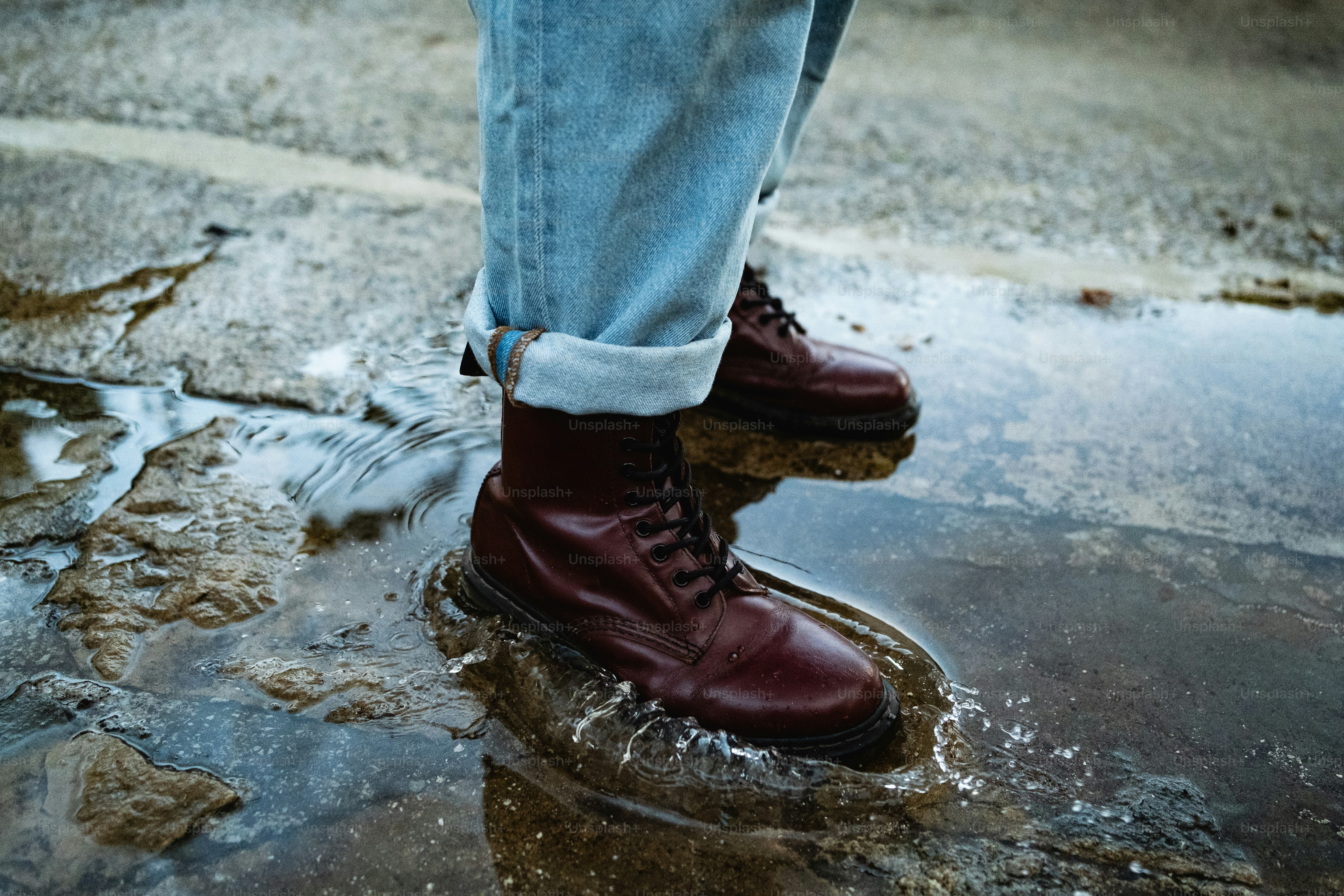 A person standing in a puddle wearing red boots