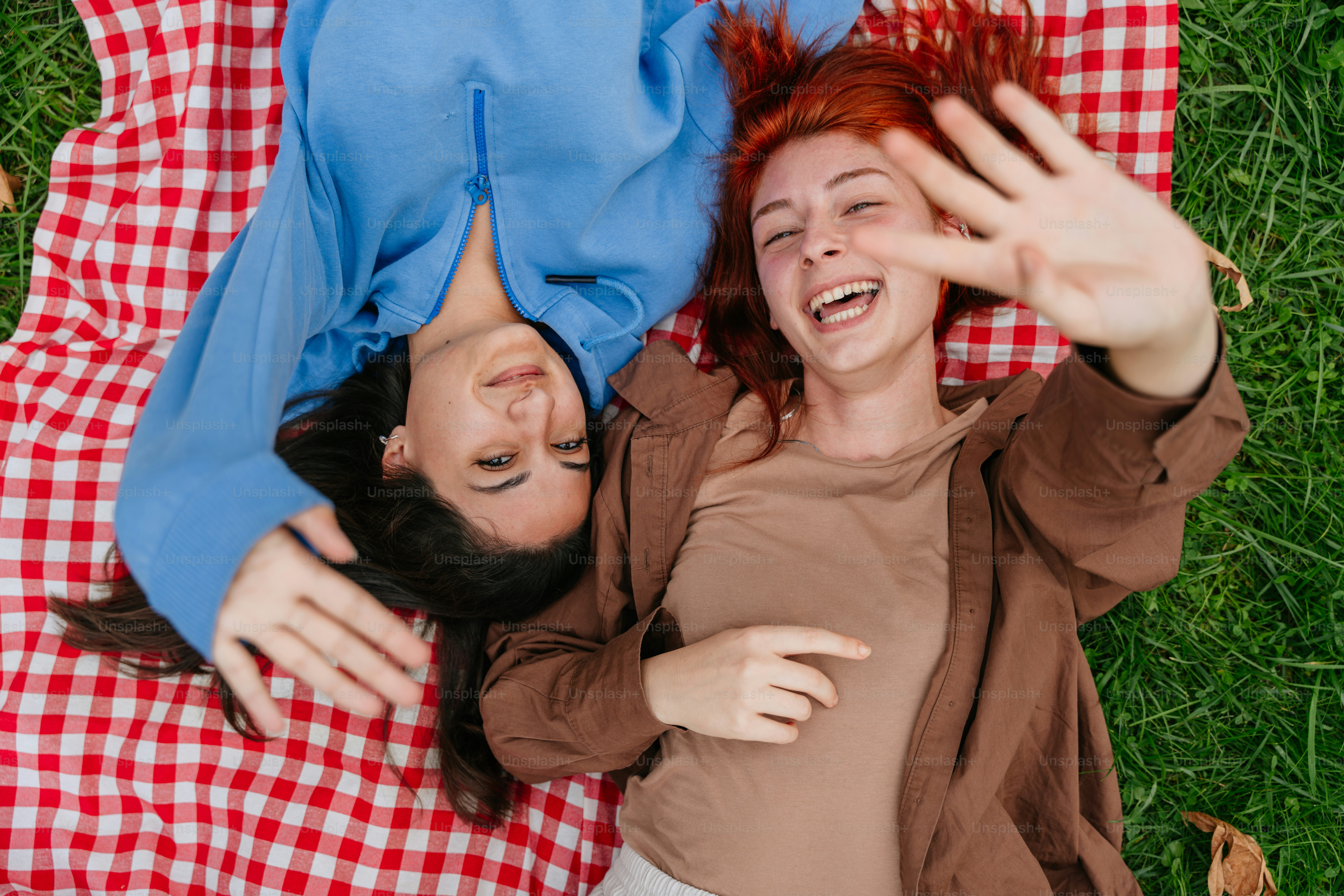A couple of people laying on top of a red and white checkered blanket