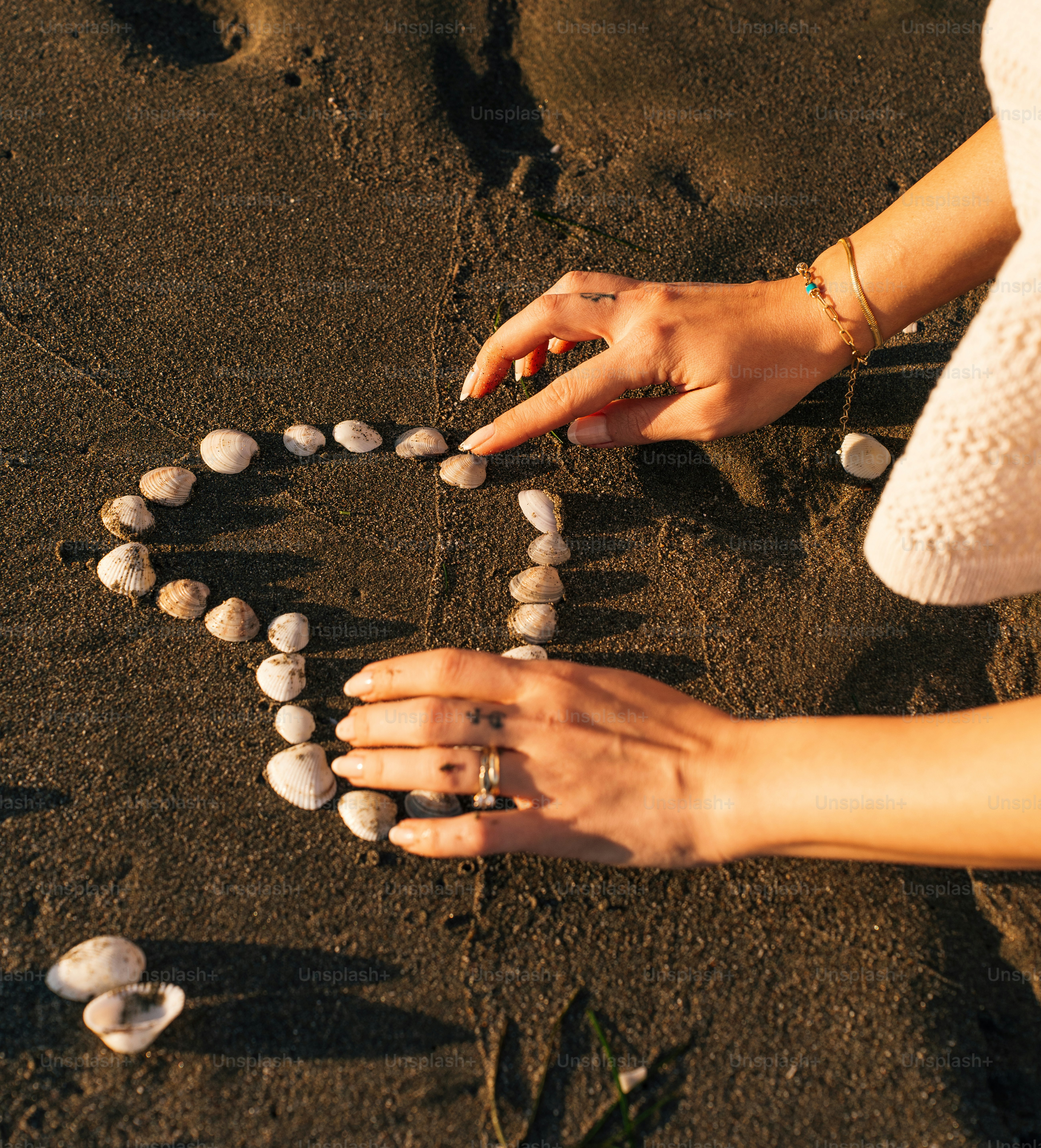 A woman is making a heart out of shells