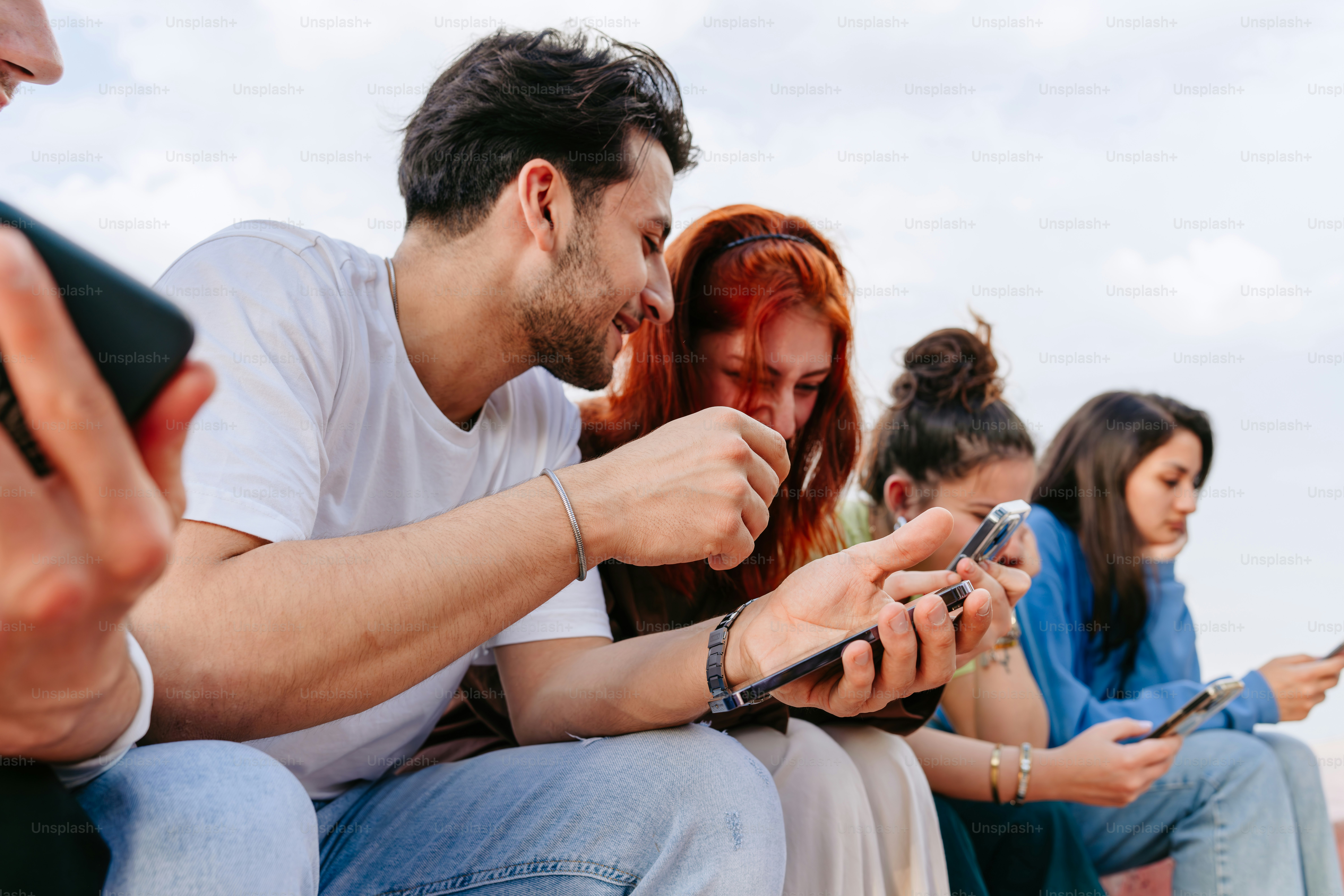 Un groupe de personnes assises les unes à côté des autres à l’aide de téléphones portables