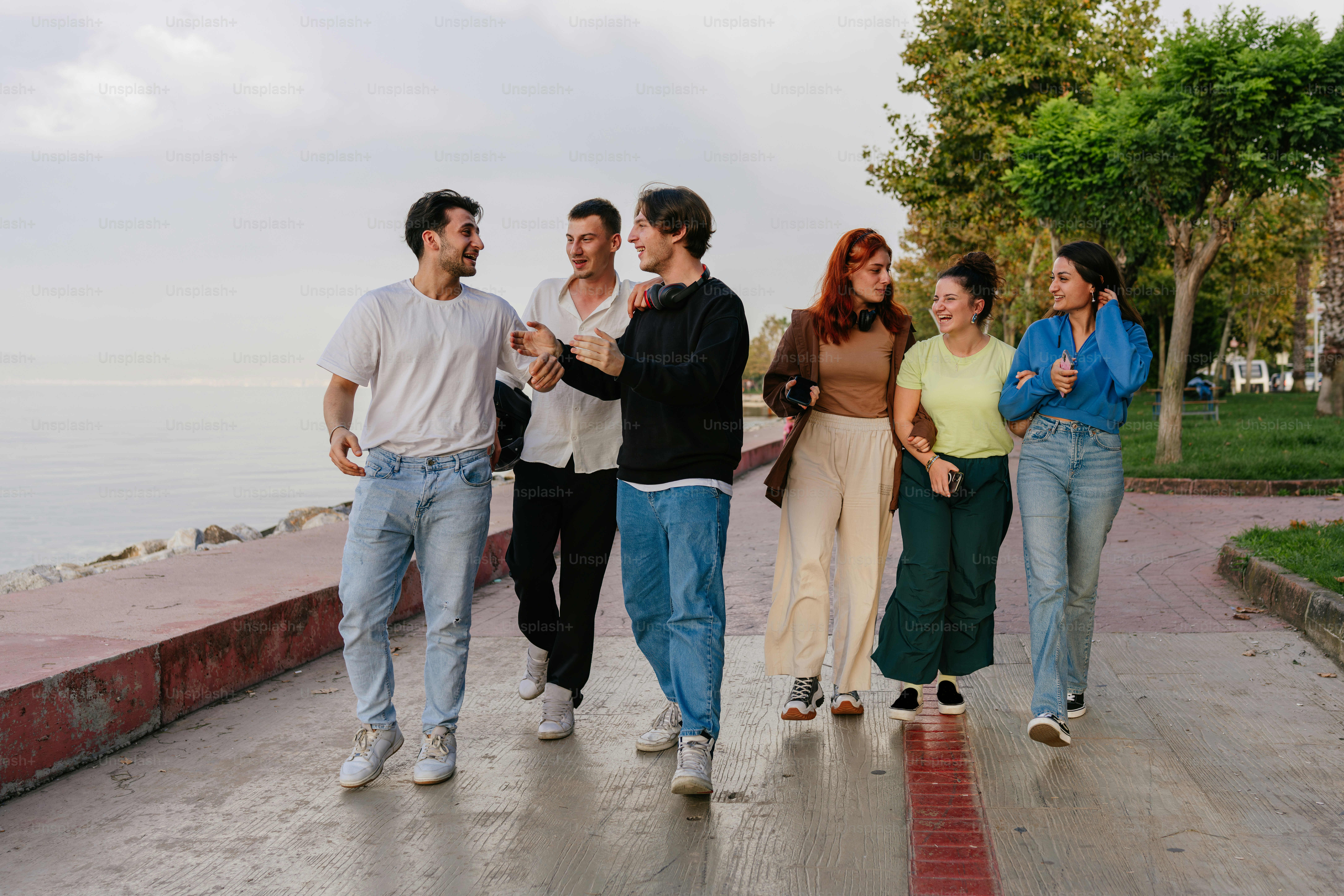 A group of people walking down a sidewalk next to a body of water
