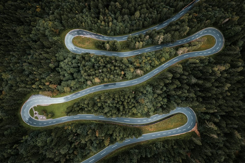 Aerial view of a two-lane road curving through dense forest