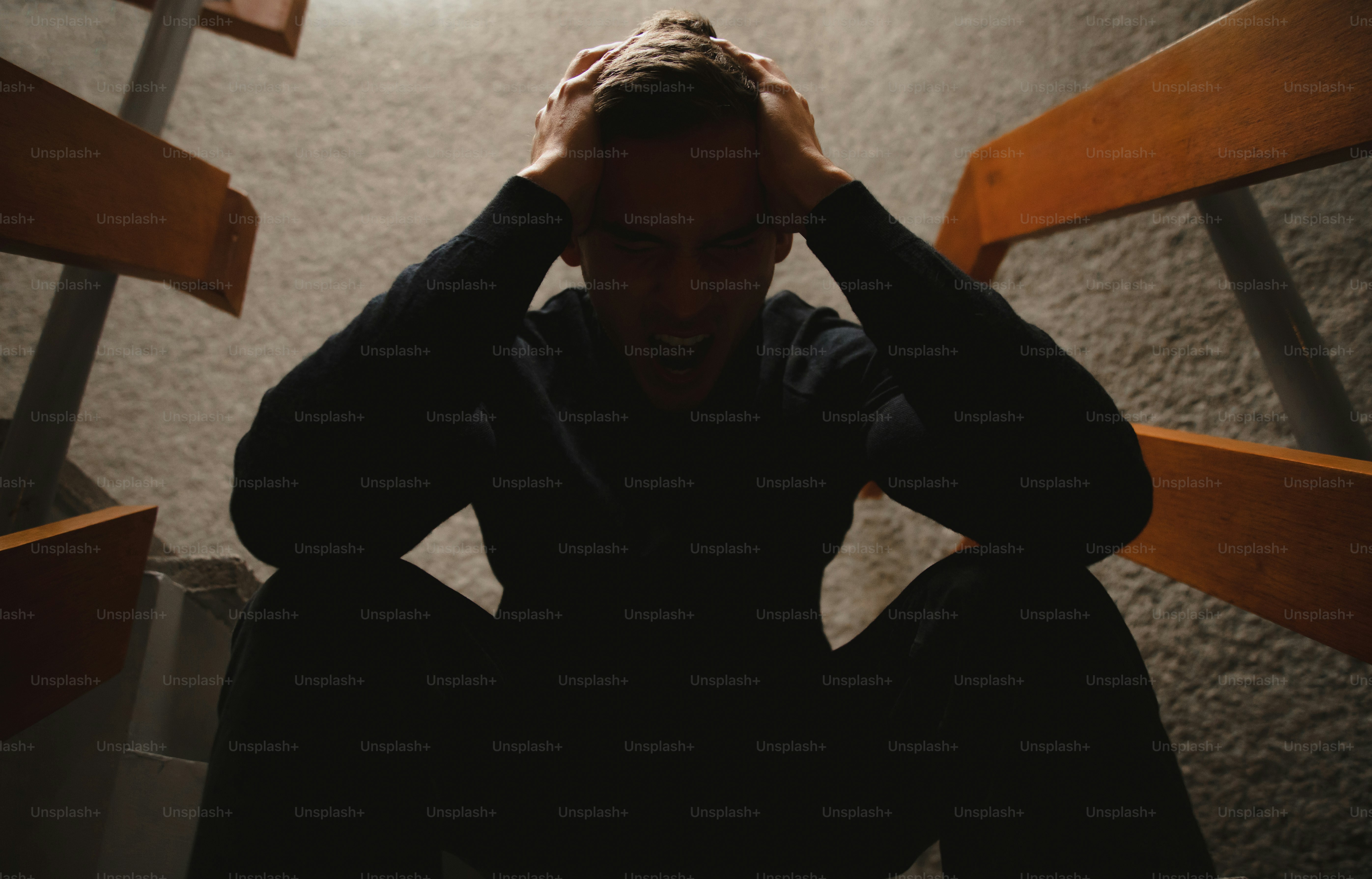 A man is sitting on the stairs with his head in his hands