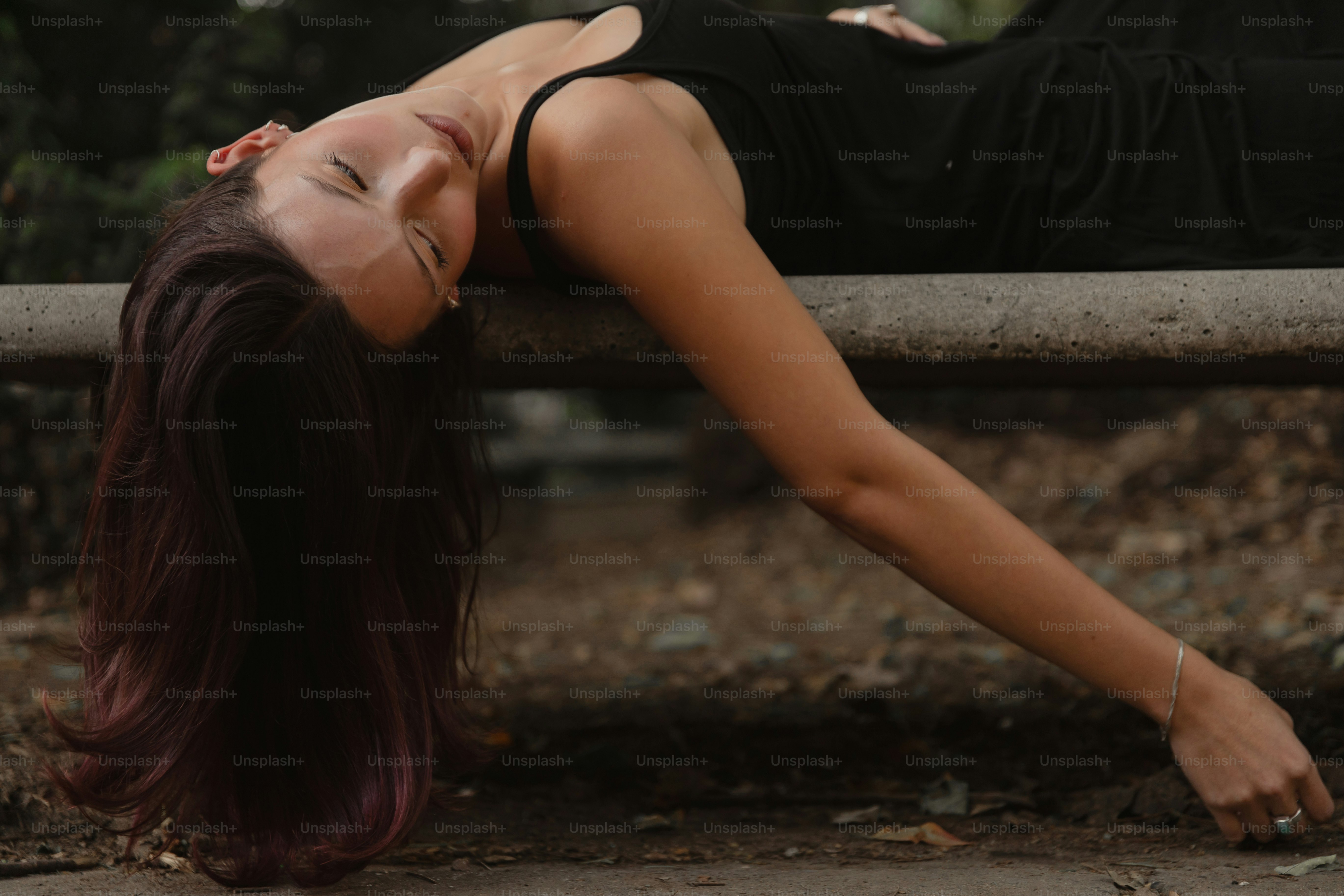 A woman in a black dress laying on a bench