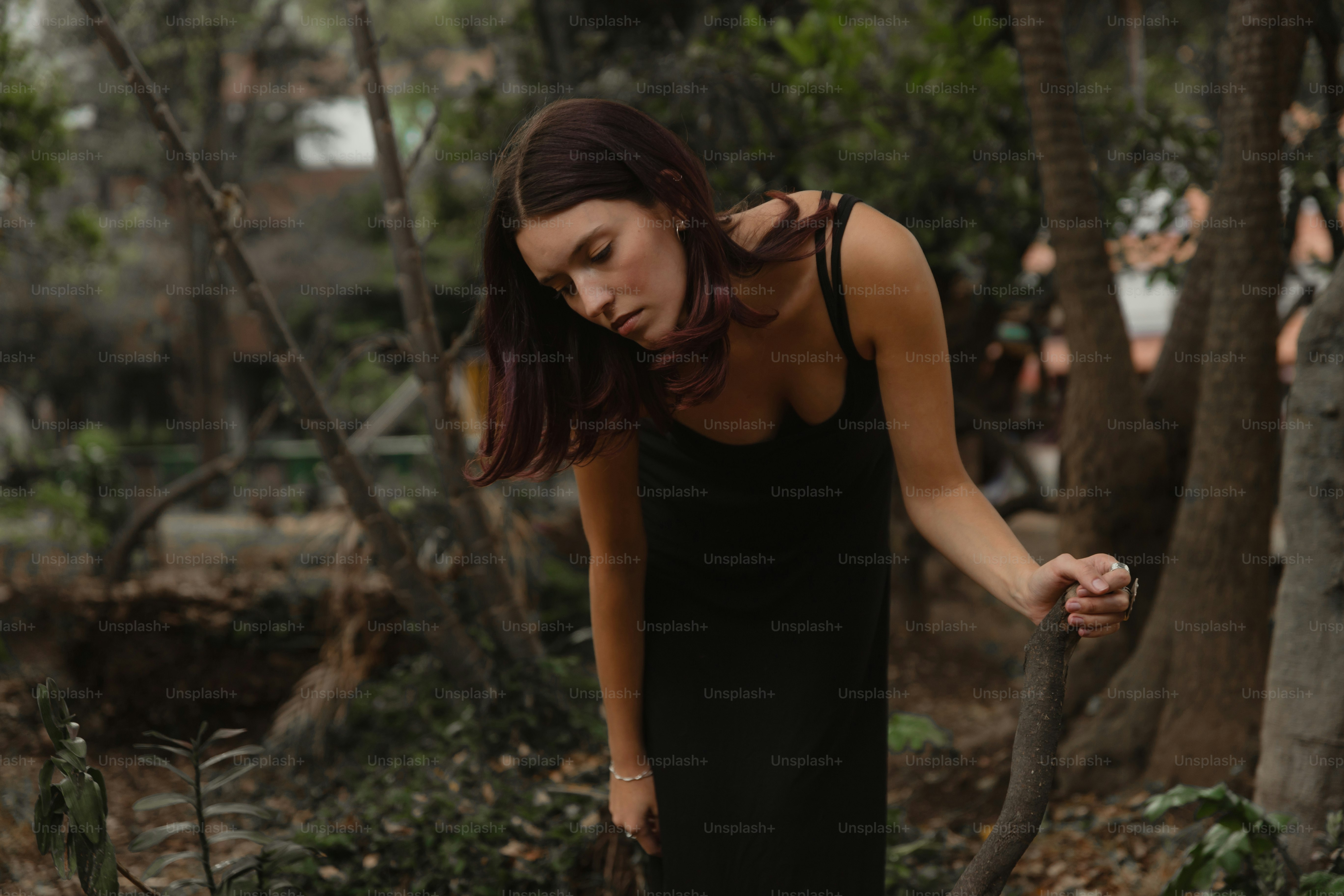 A woman in a black dress walking through a forest