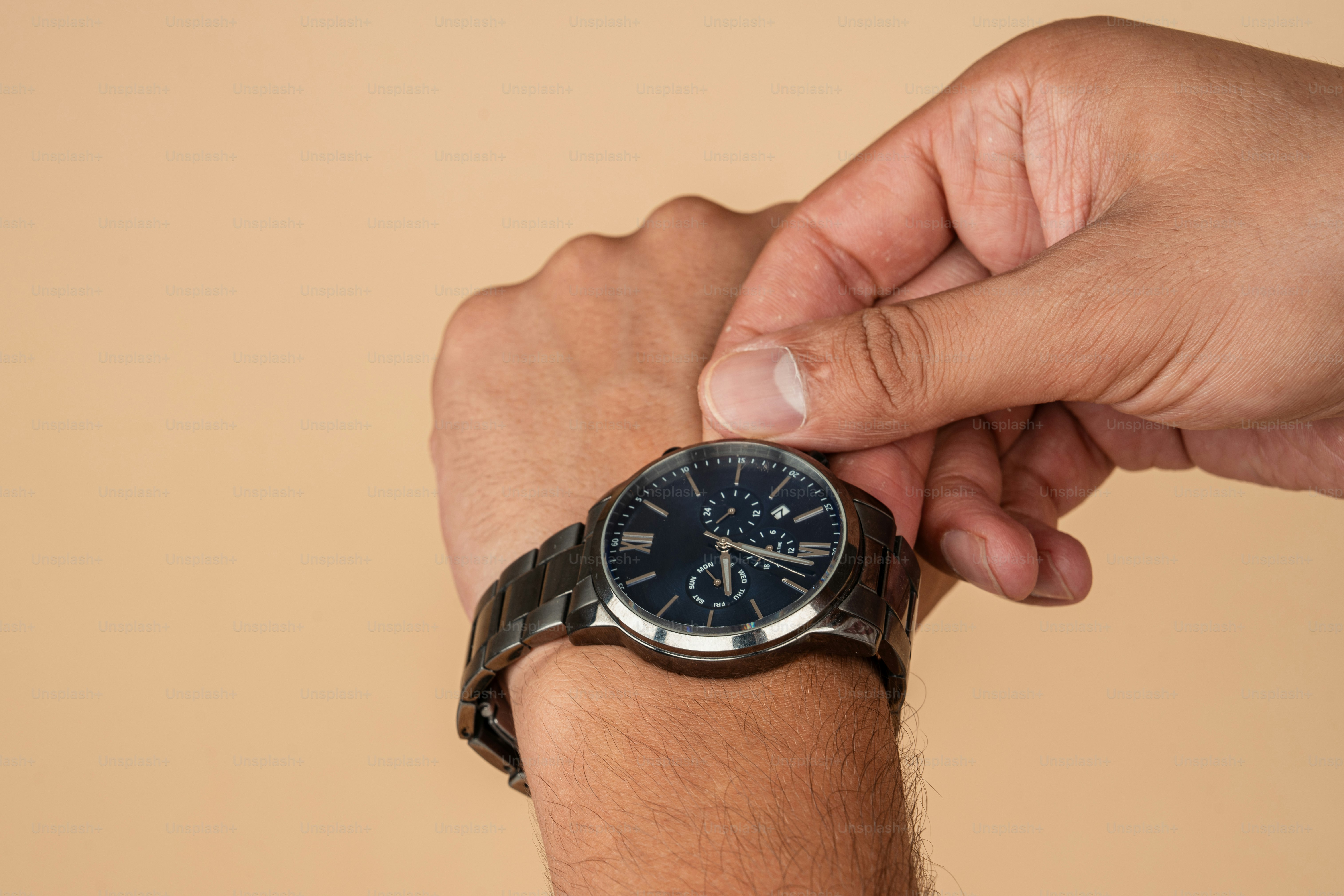 A man holding onto his wrist with a watch on it