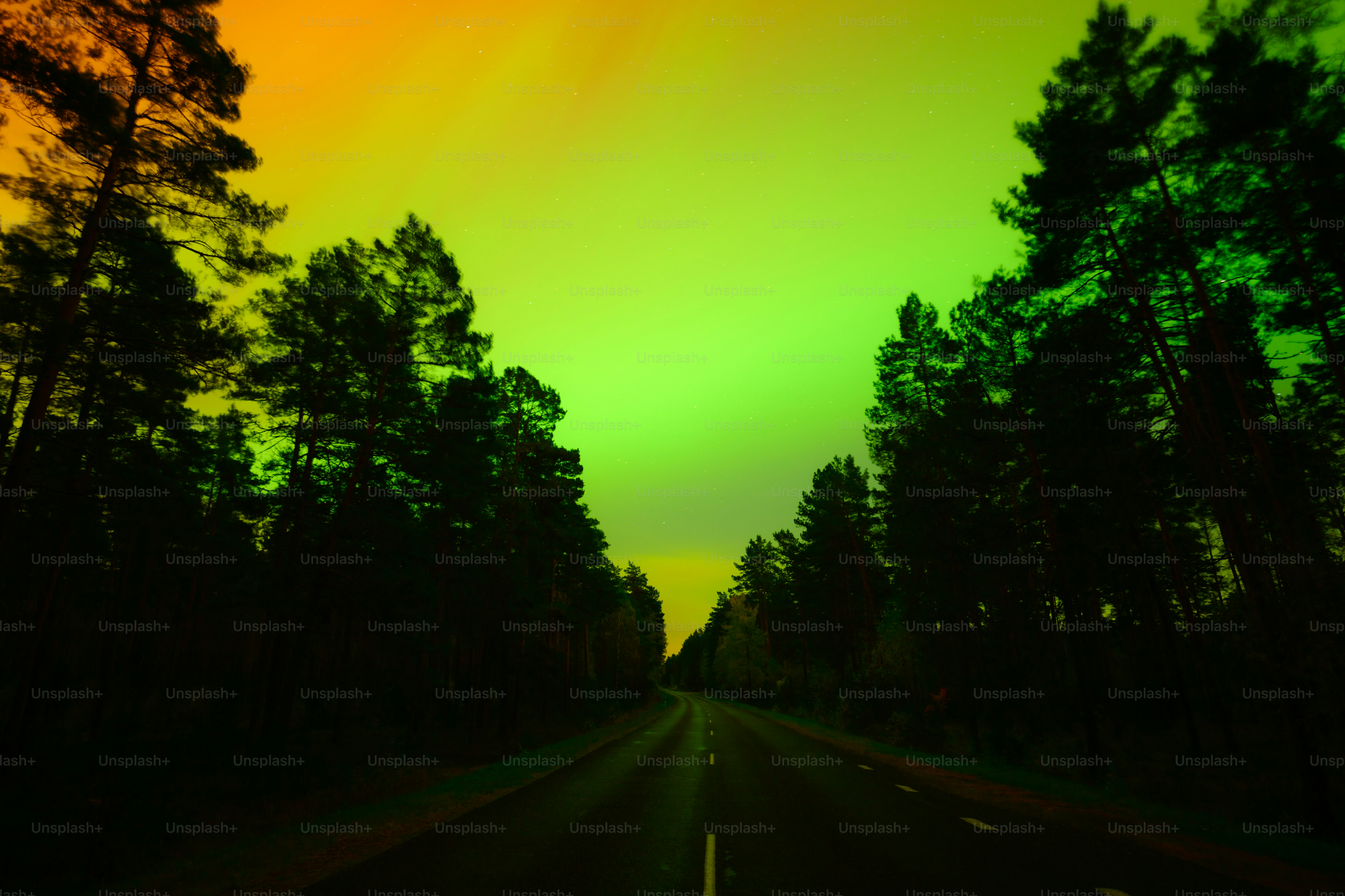 A dock in the middle of a body of water under a green and yellow aurora ...