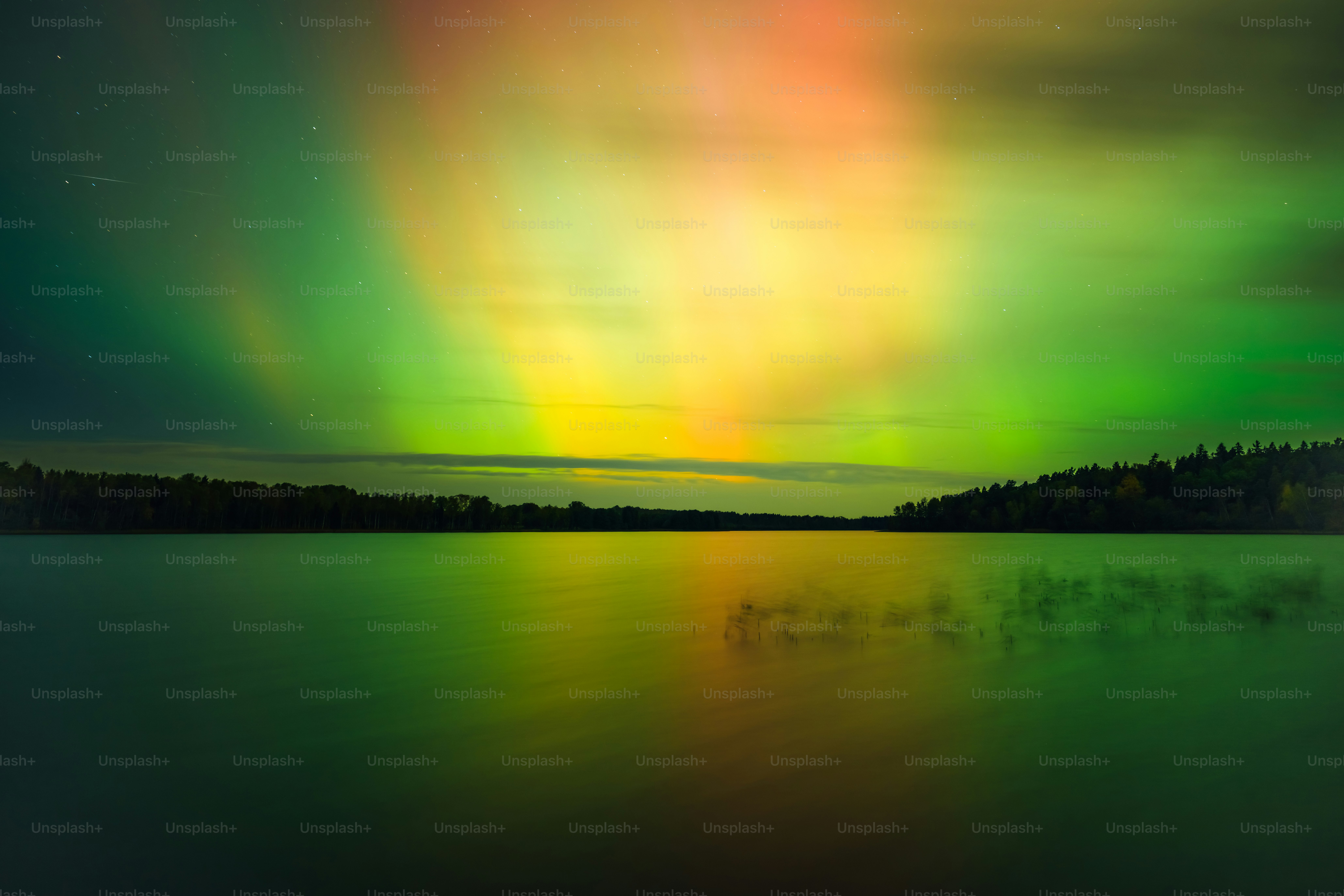 A dock in the middle of a body of water under a green and yellow aurora ...