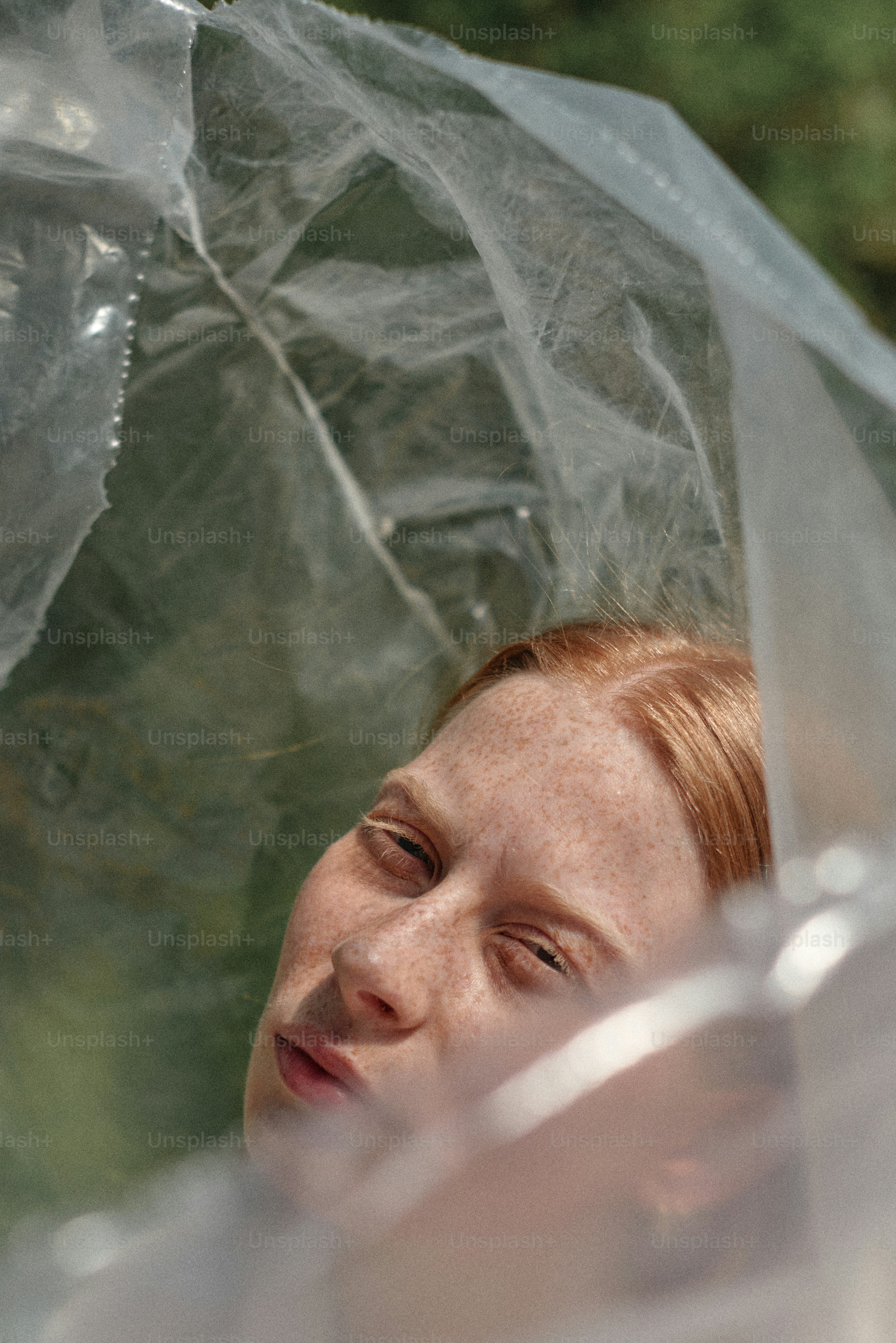 Eine Frau mit roten Haaren hält einen durchsichtigen Regenschirm in der Hand
