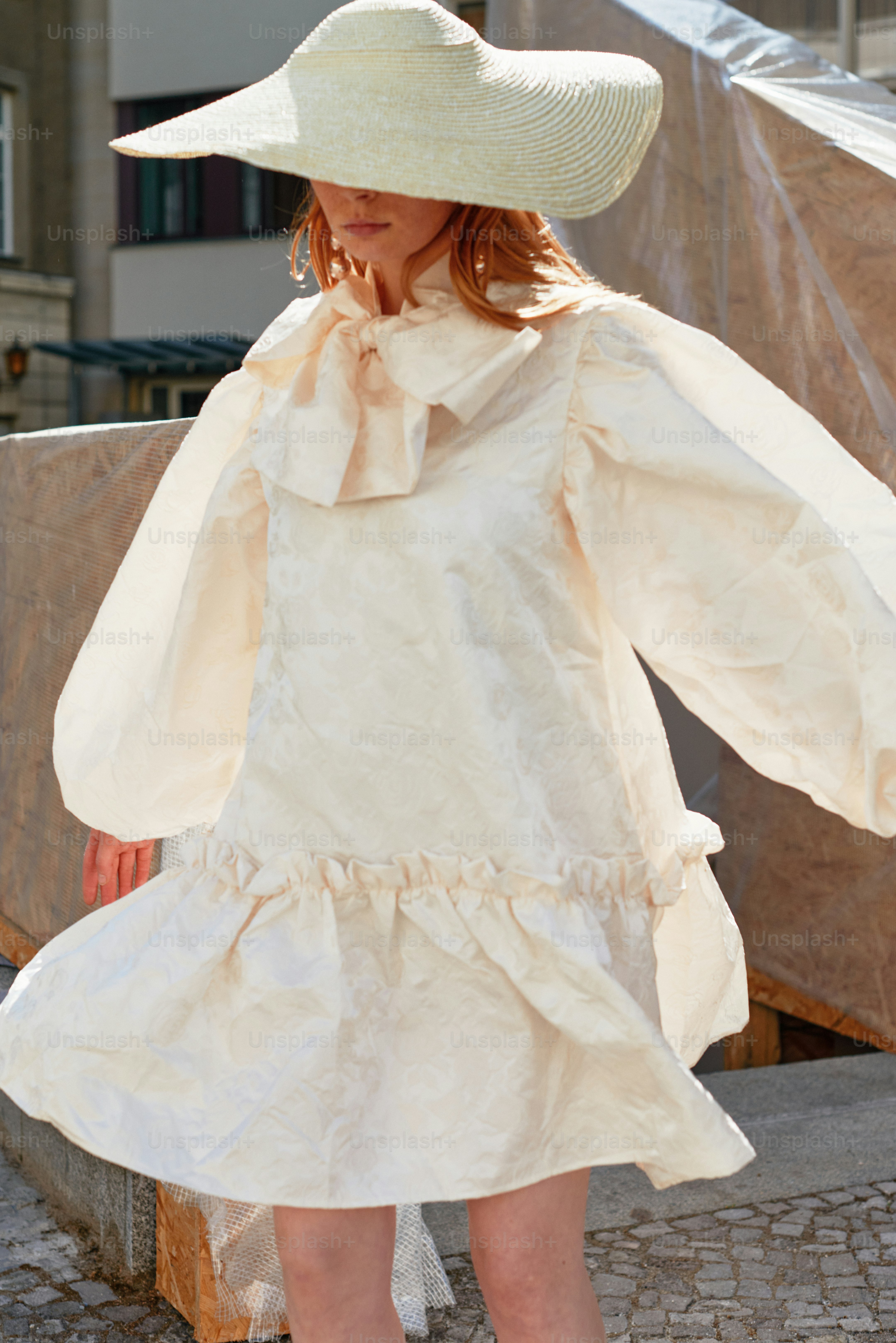 A little girl in a white dress and hat