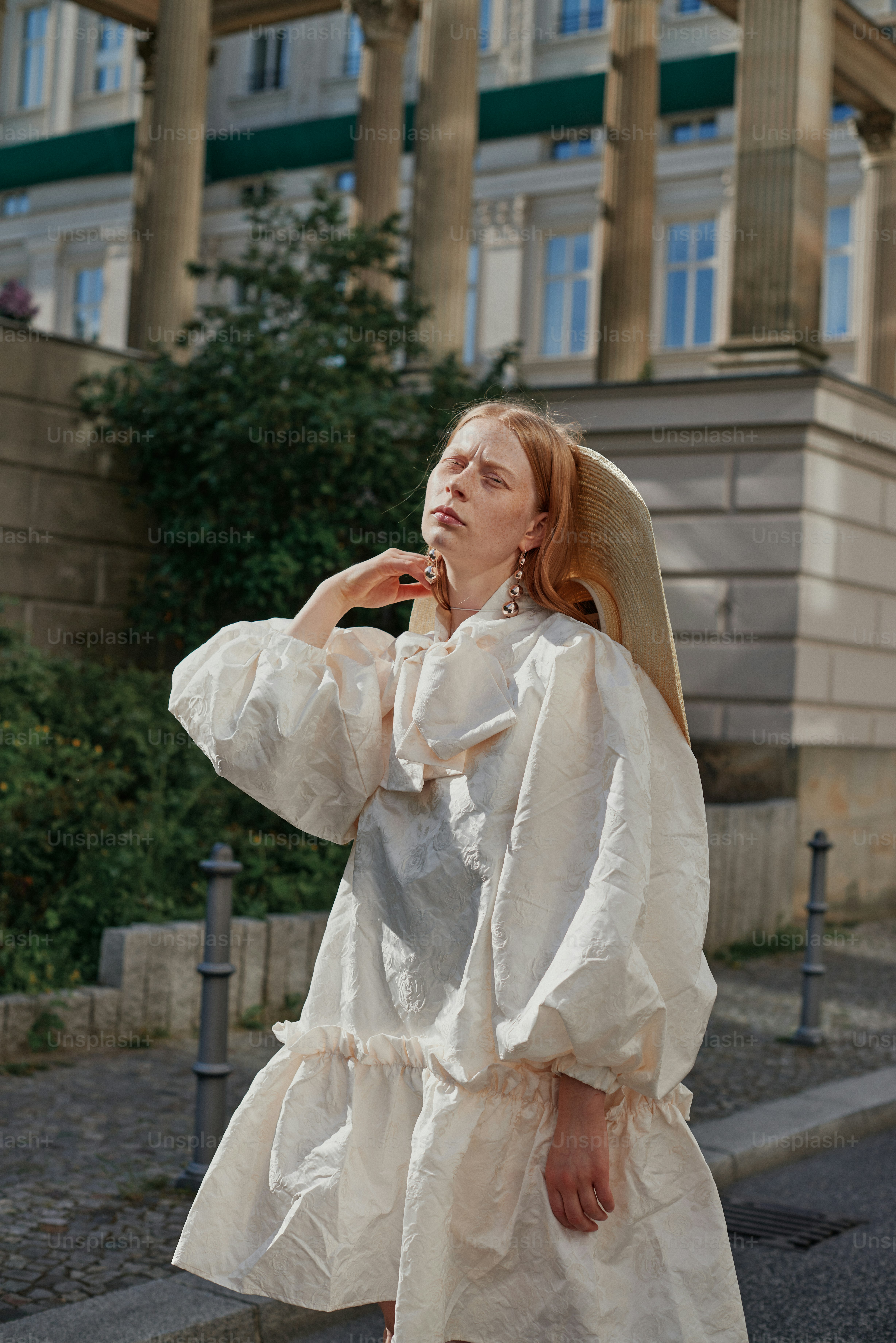 A woman in a white dress is walking down the street