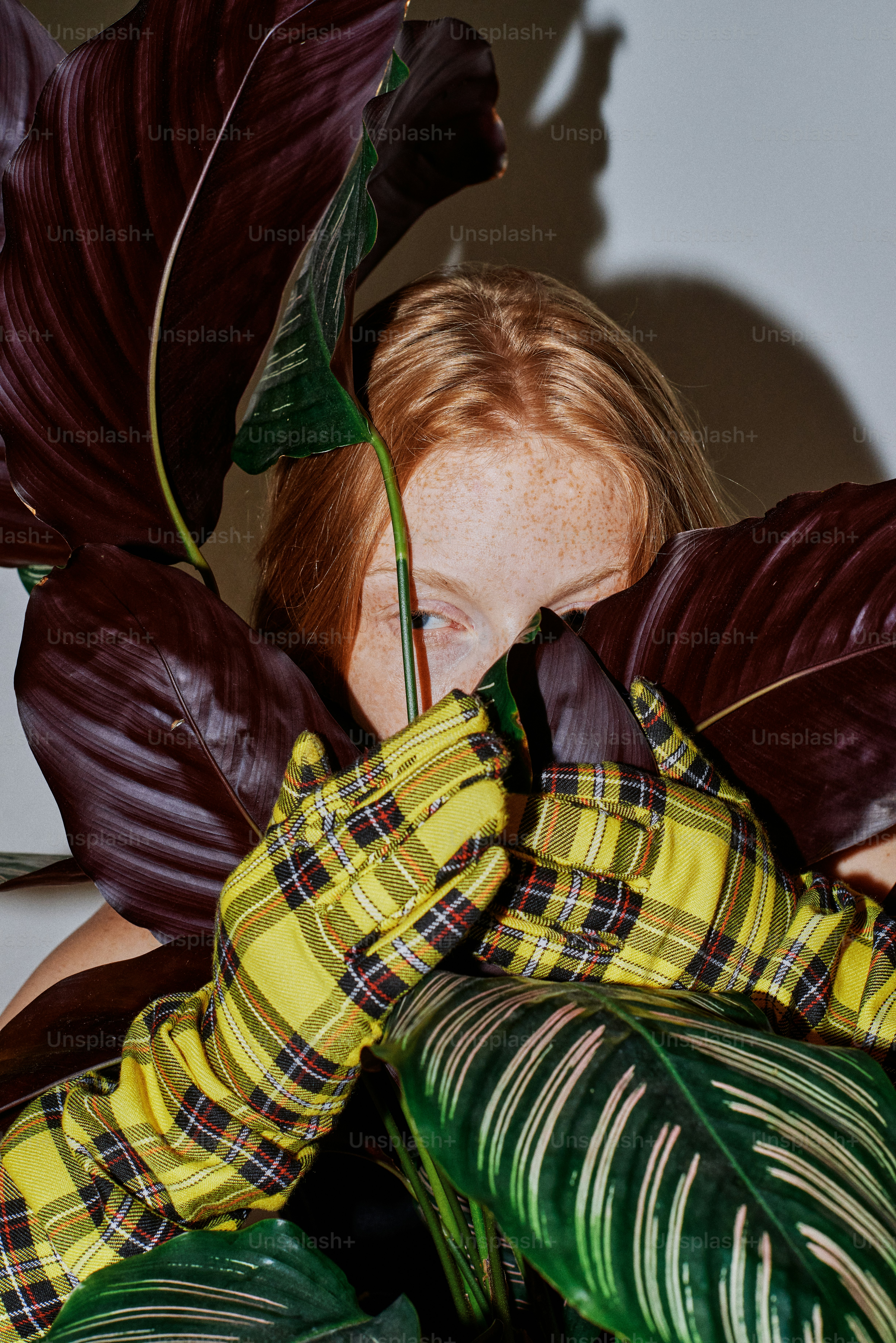 A young girl hiding behind a large leaf