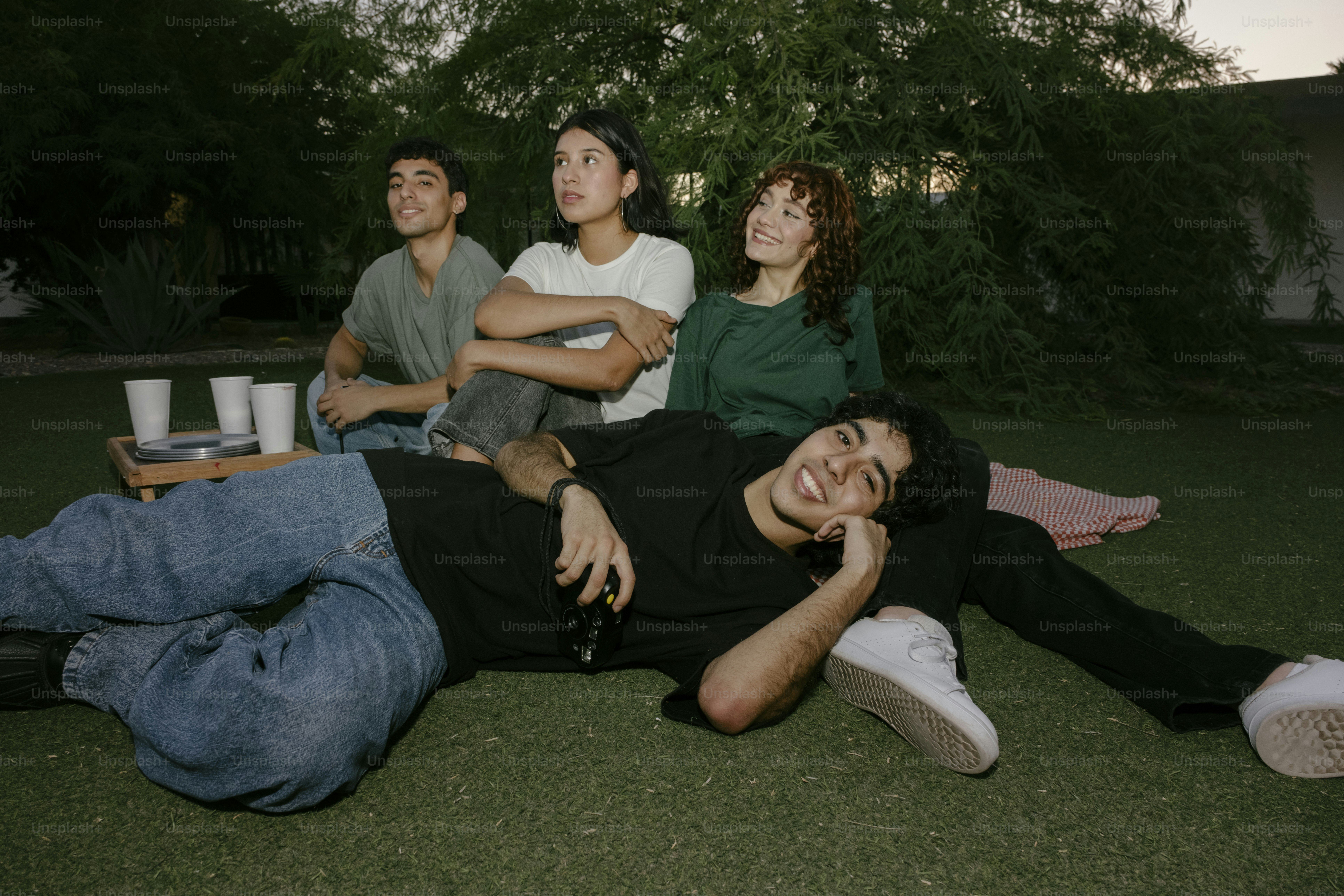 A group of people sitting on top of a lush green field