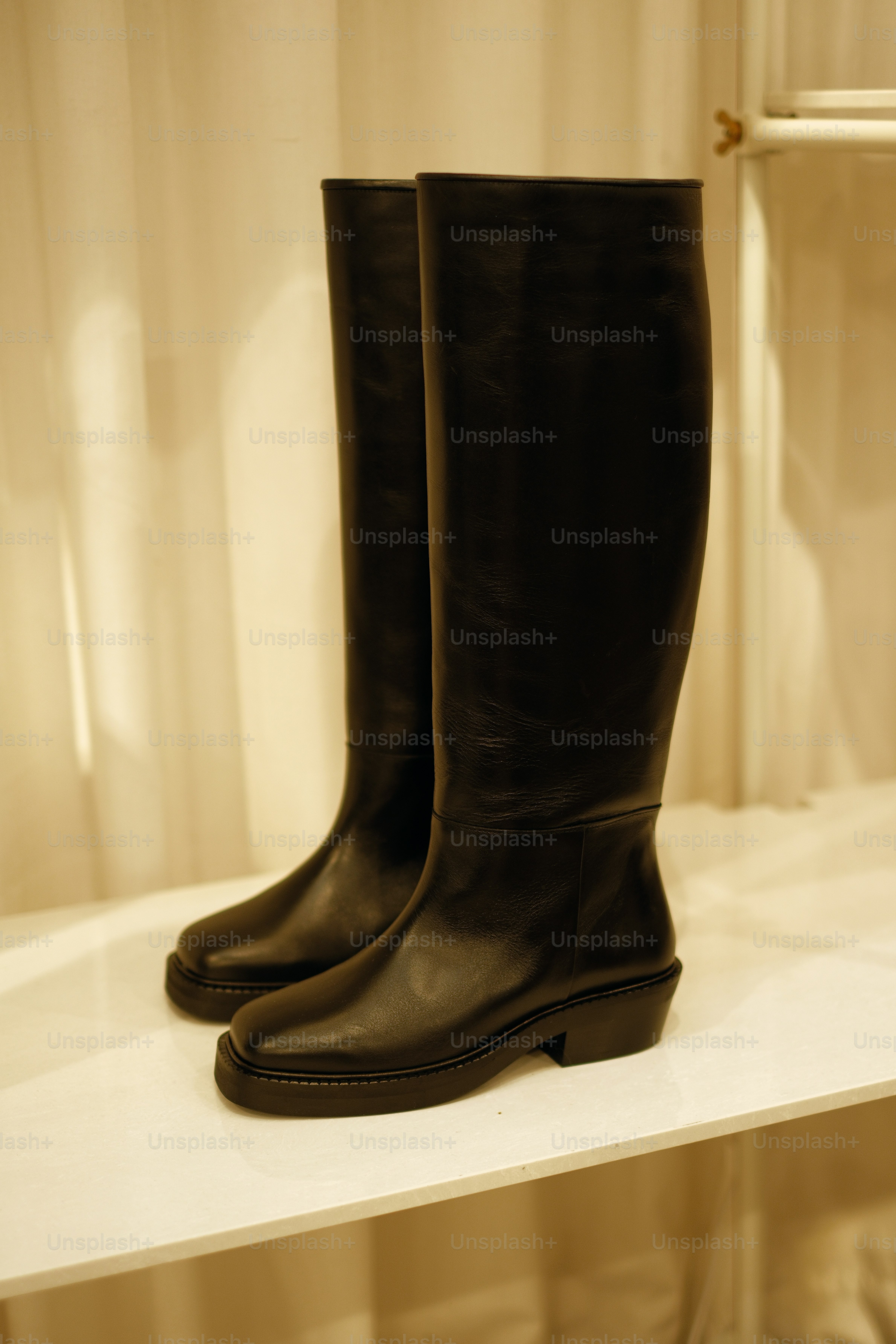A pair of black boots sitting on top of a white shelf