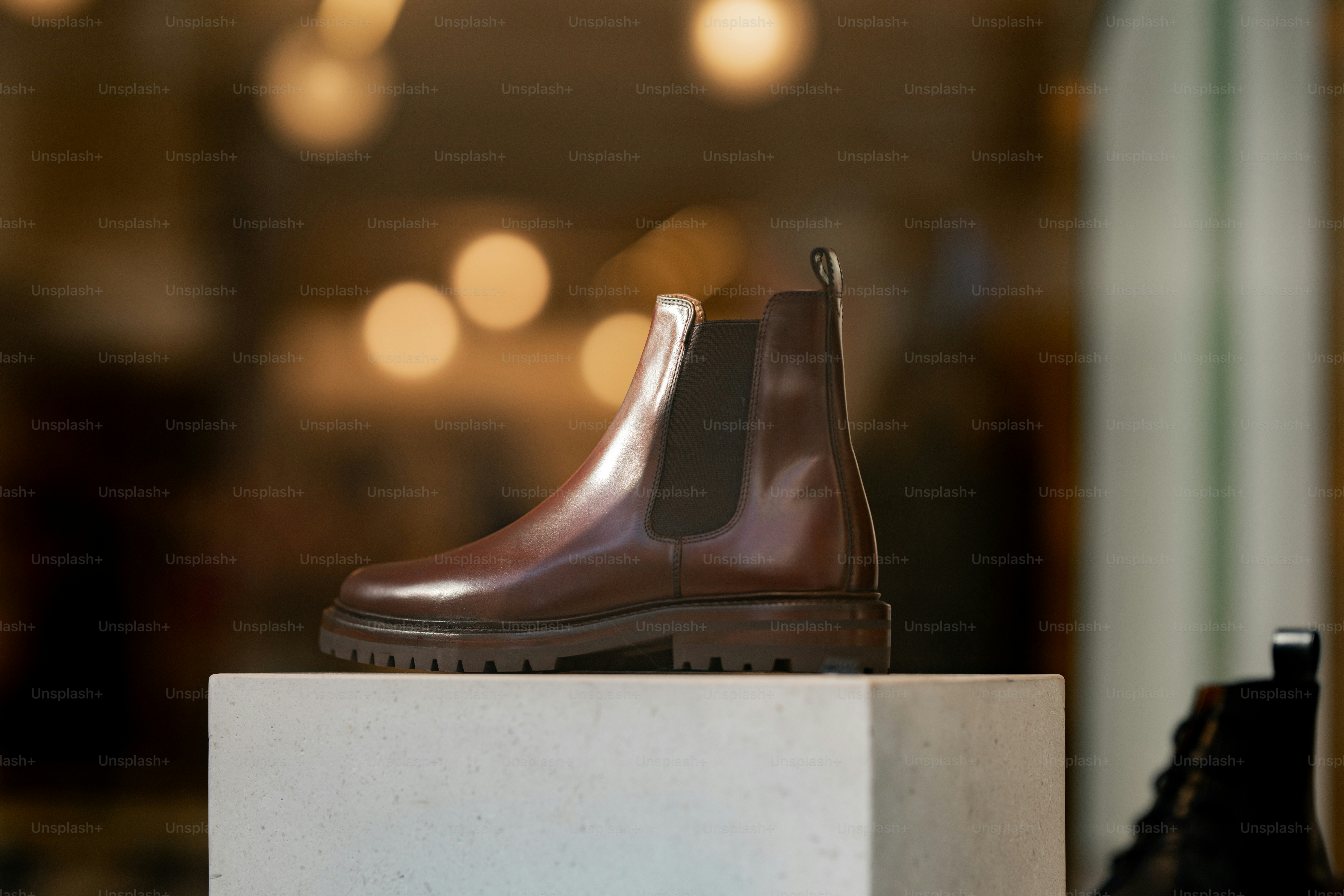 A pair of brown boots sitting on top of a white block